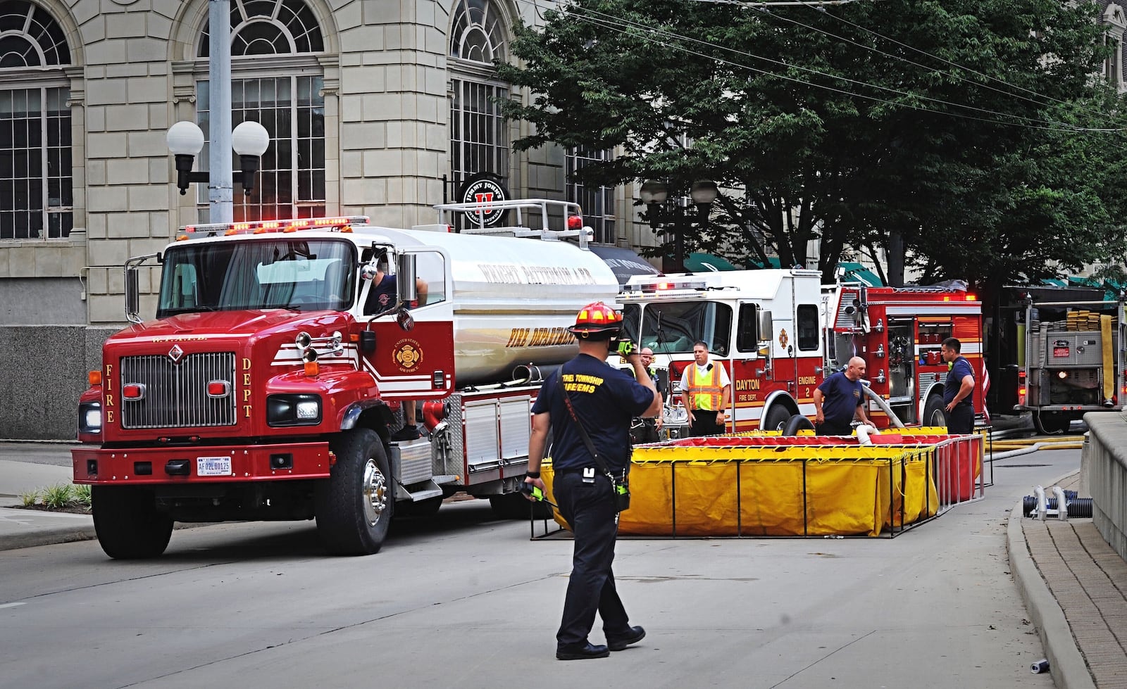 Crews set up portable water tanks to help battle a fire at the historic Biltmore Towers senior apartment building at 210 N. Main St. in Dayton. The fire occurred as the city was experiencing water pressure issues due to a water main break Monday, Aug. 3, 2020. MARSHALL GORBY / STAFF