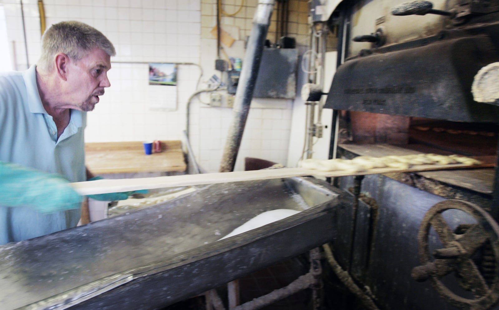 Larry Smales loads his hand-rolled  "Pennsylvania Dutch"  pretzels into a 50-year-old oven with a revolving stone floor that's never allowed to cool. Jim Noelker/Dayton Daily News