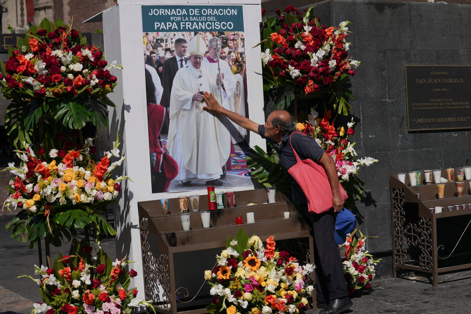 A parishioner touches an image of Pope Fransisco during a prayer service for his health outside of the Basilica of Guadalupe in Mexico City, Monday, Feb. 24, 2025. (AP Photo/Marco Ugarte)