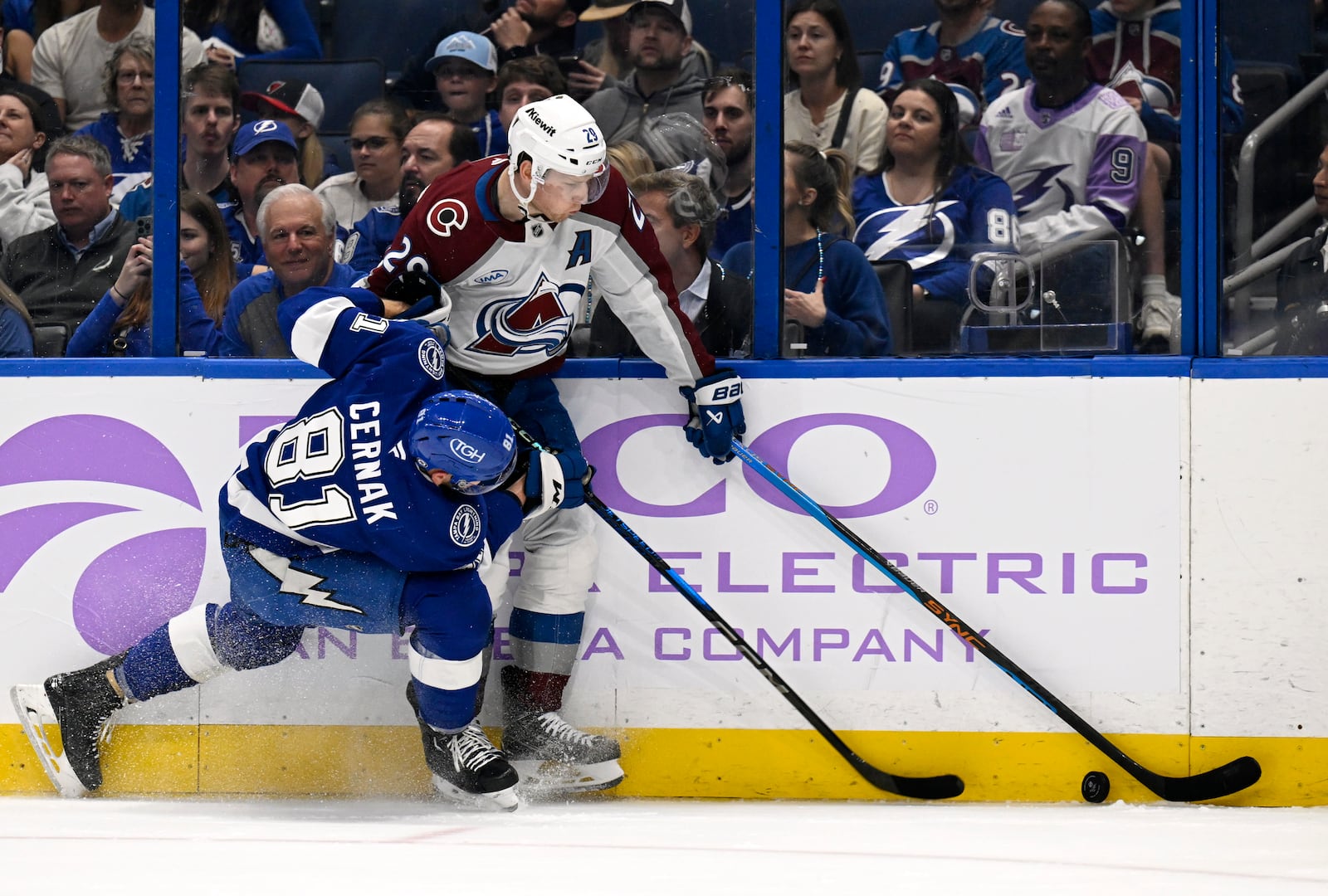 Tampa Bay Lightning defenseman Erik Cernak (81) and Colorado Avalanche center Nathan MacKinnon (29) battle for the puck during the first period of an NHL hockey game Monday, Nov. 25, 2024, in Tampa, Fla. (AP Photo/Jason Behnken)