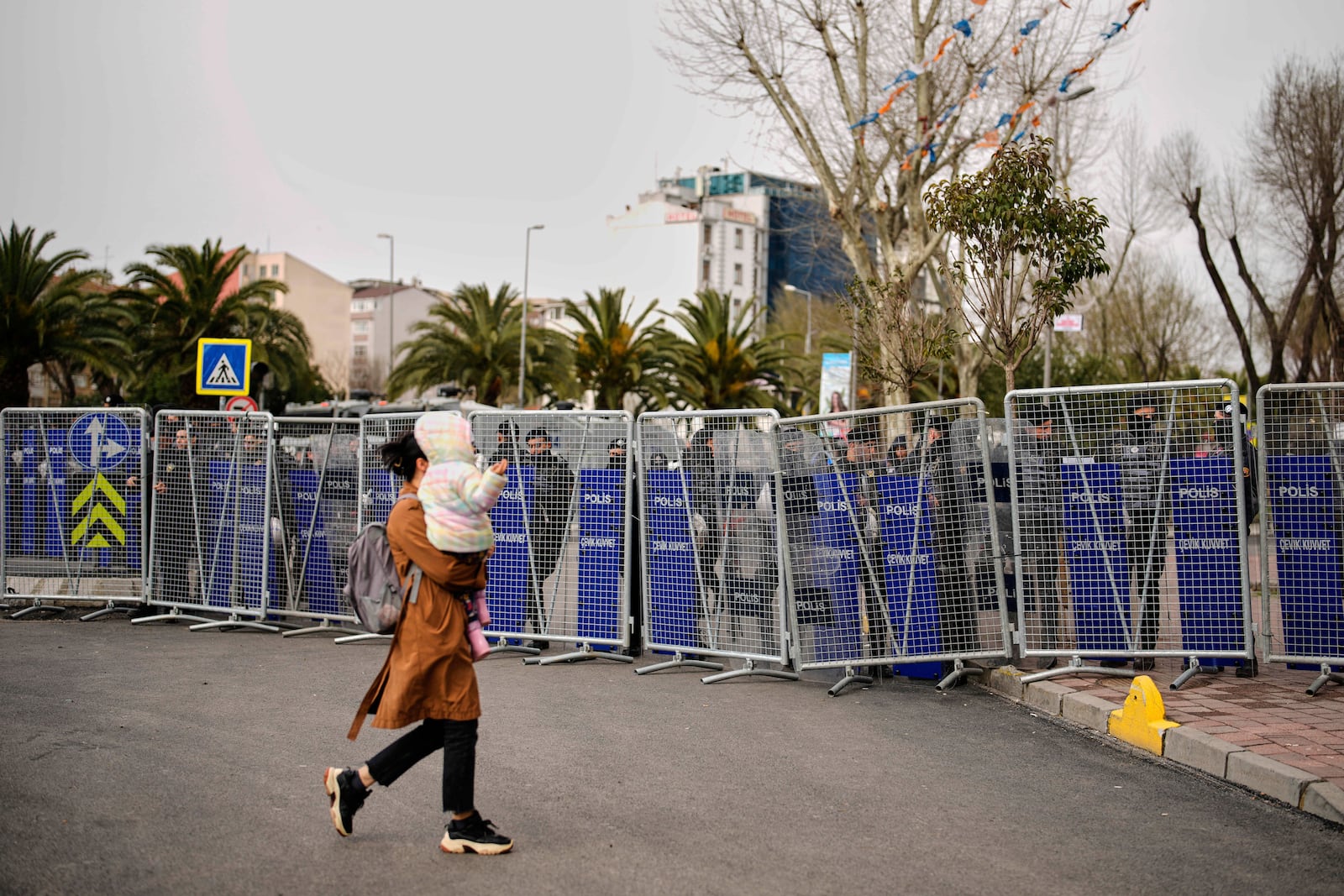 A woman walks past police cordons blocking the roads leading to the Vatan Security Department, where Istanbul Mayor Ekrem Imamoglu is expected to be taken following his arrest in Istanbul, Turkey, Wednesday, March 19, 2025. (AP Photo/Emrah Gurel)