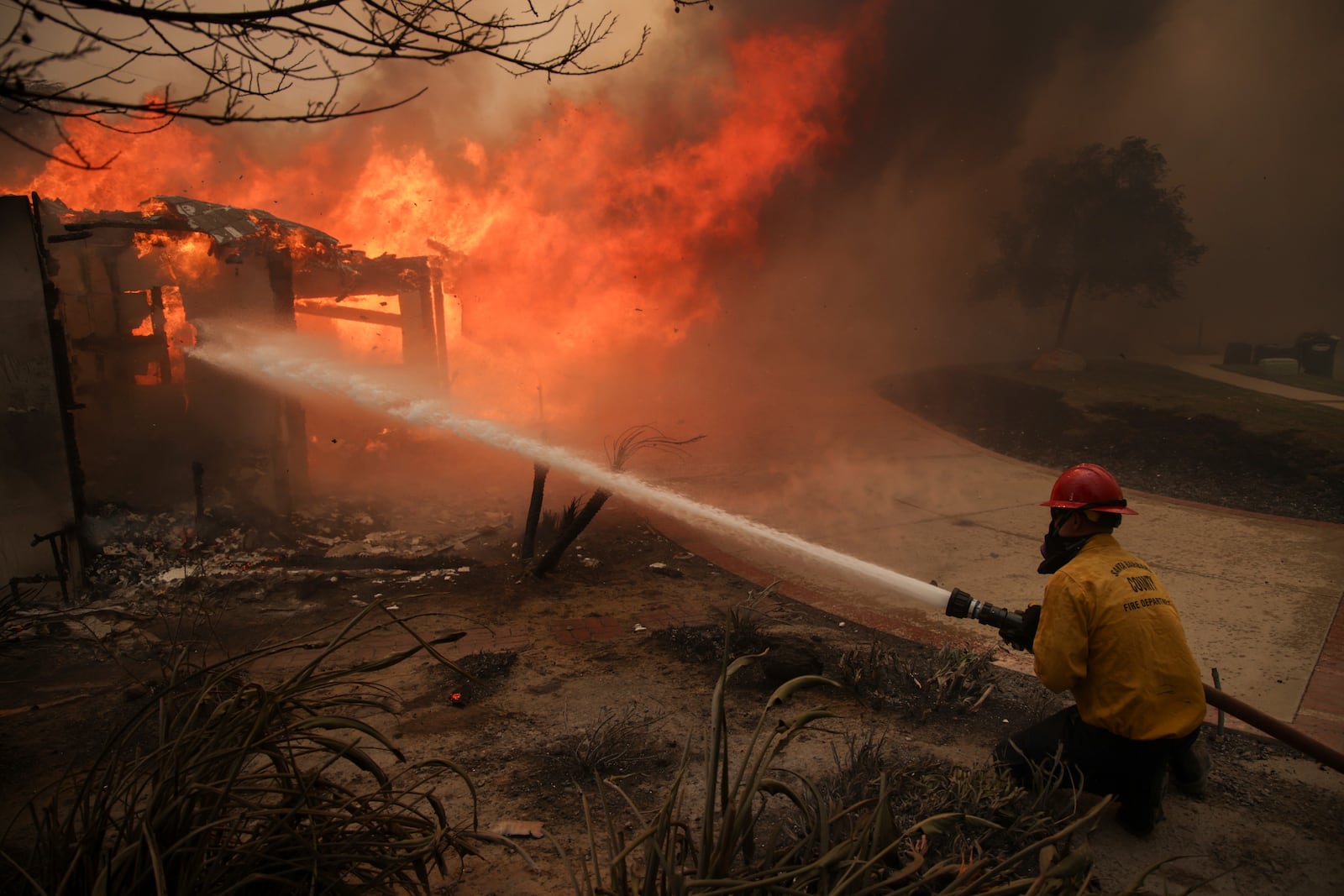 Firefighters spray water on a burning structure during the Mountain Fire, Wednesday, Nov. 6, 2024, near Camarillo, Calif. (AP Photo/Ethan Swope)