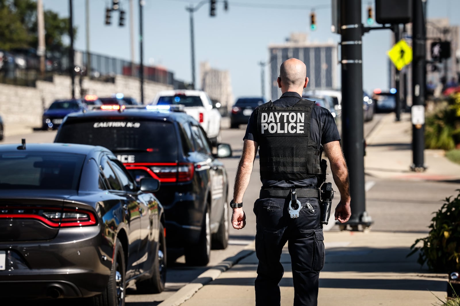 A Dayton police officer walks up Main Street toward Miami Valley Hospital as Richmond, Indiana, and Dayton police cruisers line the street Thursday, Sept. 1, 2022. Officers lined up in support of Richmond officer Seara Burton, who was shot Aug. 10 in the line of duty. She was taken off life support. JIM NOELKER/STAFF