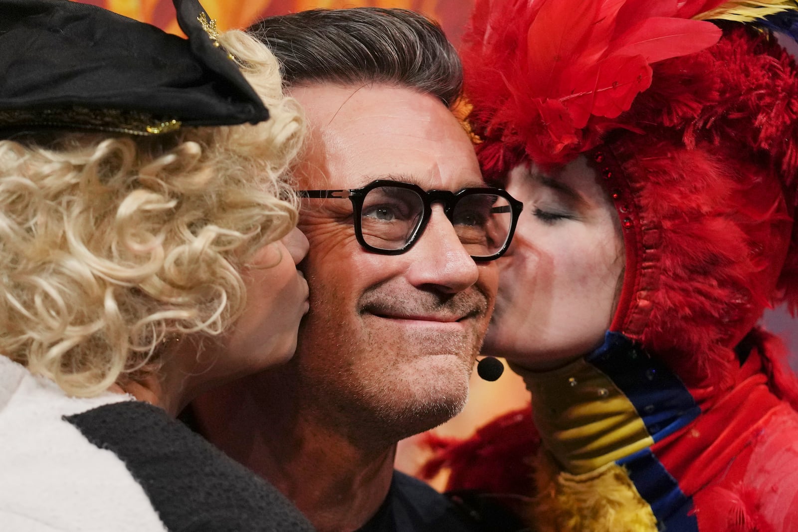 Harvard University's Hasty Pudding Theatricals Man of the Year Jon Hamm is kissed by character actors while holding his award, Friday, Jan. 31, 2025, in Cambridge, Mass. (AP Photo/Charles Krupa)