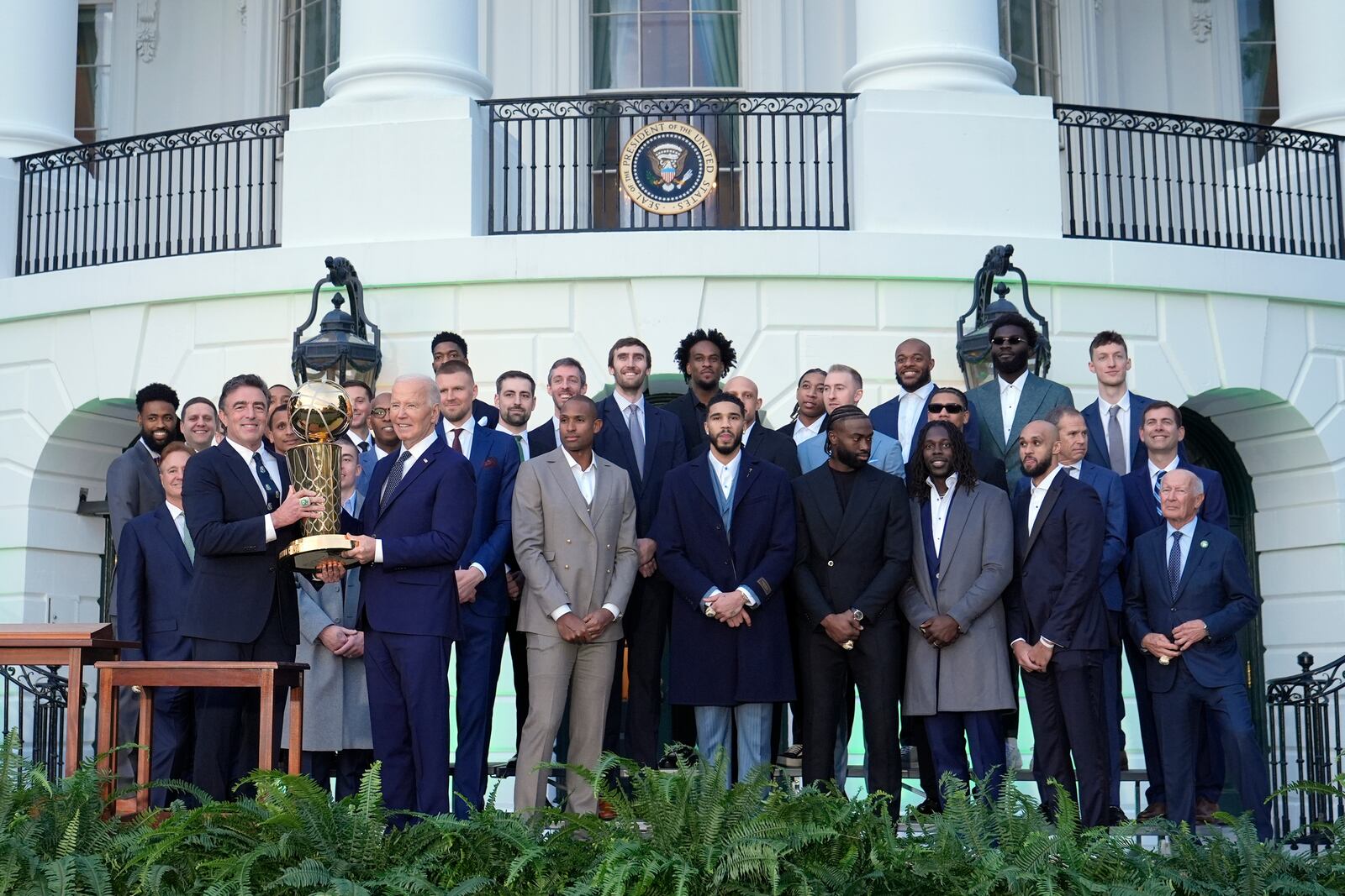 Boston Celtics owner Wyc Grousbeck, from left, and President Joe Biden hold up the Boston Celtics trophy as they pose for a team photo to celebrate the Celtics victory in the 2024 National Basketball Association Championship during an event on the South Lawn of the White House in Washington, Thursday, Nov. 21, 2024. (AP Photo/Susan Walsh)