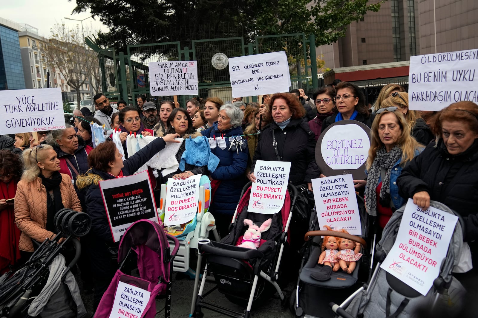 Activists, some holding banners with Turkish writing that some of them reads, " Children should not be killed , so they can eat candies", " I couldn't play with my toys because I was killed" and " If I had not been killed this toy would have been my sleeping friend " during a protest outside the courthouse where dozens of Turkish healthcare workers including doctors and nurses go on trial for fraud and causing the deaths of 10 infants, in Istanbul, Turkey, Monday Nov, 18, 2024.(AP Photo/Khalil Hamra)