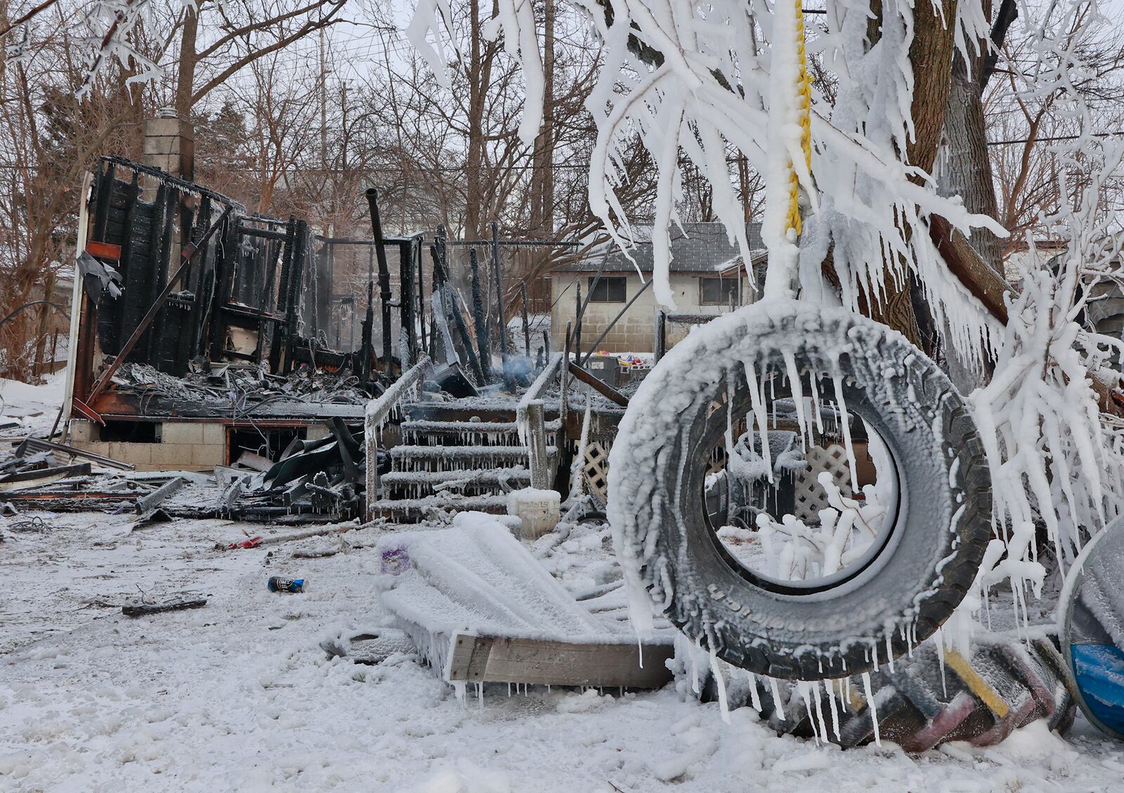 A tire swing is coated in ice in front of a smoldering remains of a house in the 300 block of Lyle Avenue in Springfield Township Friday morning. The Springfield Township fire department responded to the fully involved fire early Friday morning, Dec. 23, 2022. Brutal cold weather and strong winds hampered firefighting efforts. BILL LACKEY/STAFF