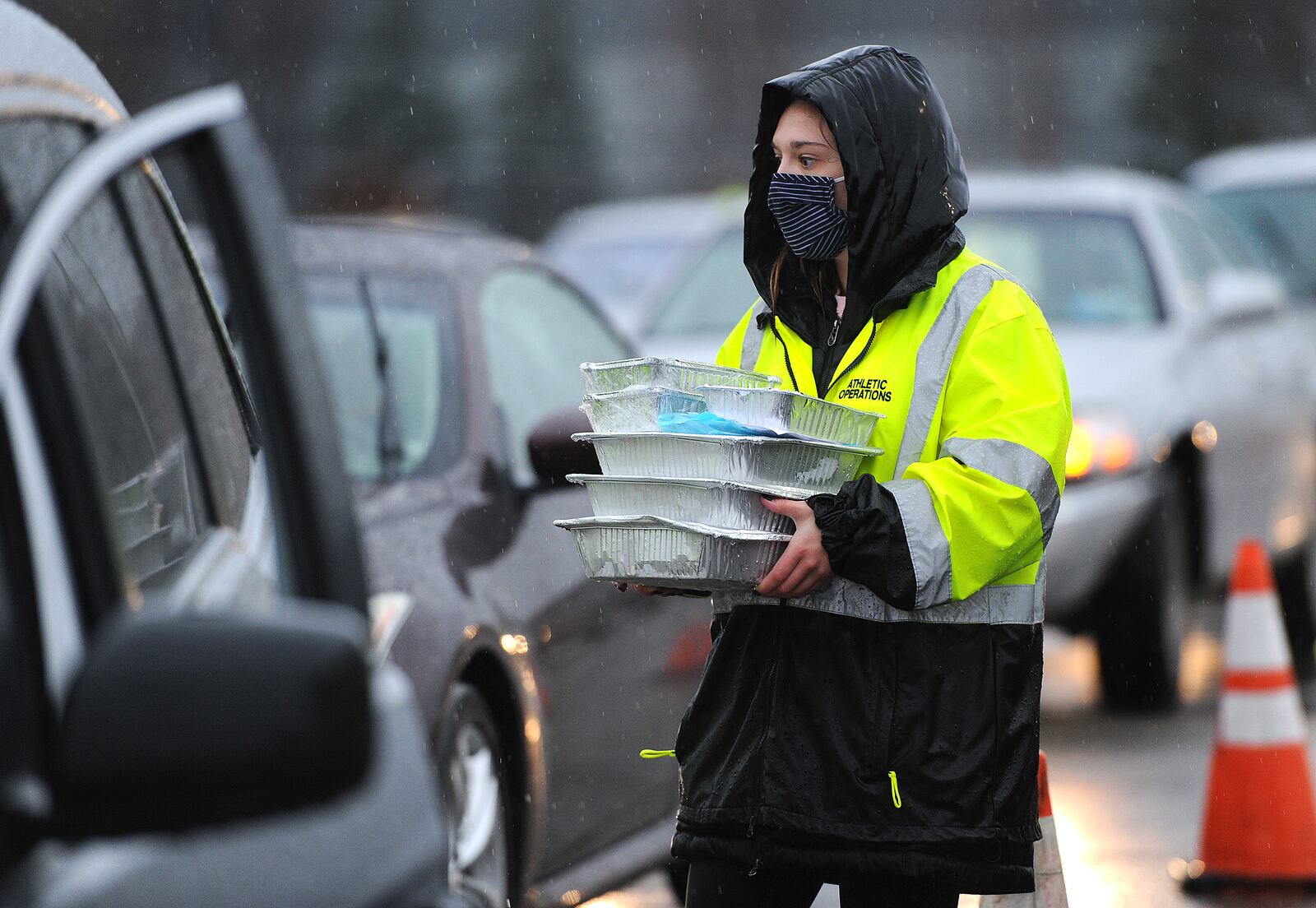 Hayley Zimbric, a sophomore at Miami University placed turkey dinners into vehicles at the University of Dayton Arena last month as Miami Valley Meals prepared about 6,000 holiday meals to be given out at the arena and Trotwood-Madison High School. MARSHALL GORBY/STAFF