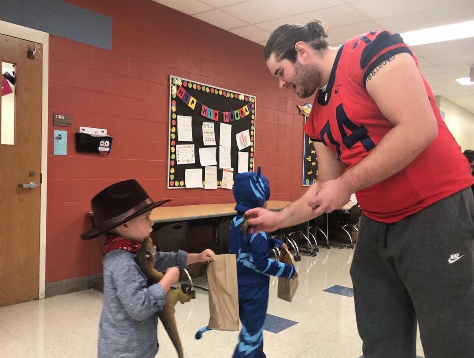 RYAN 8 – Former Dayton Flyers offensive lineman Ryan Culhane gives some candy to a young Trick-or-Treater during Halloween celebrations at Horace Mann Elementary in 2018 . CONTRIBUTED