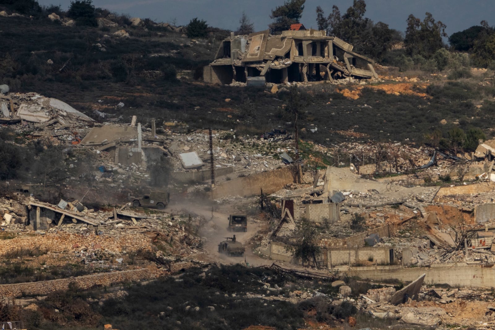 Israeli soldiers drive inside a village in southern Lebanon, as seen form northern Israel, Thursday, Jan. 23, 2025. (AP Photo/Ariel Schalit)