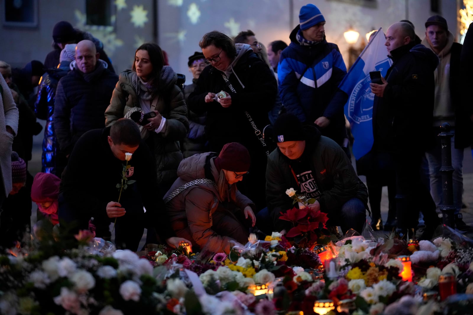 Citizens pay tribute for deaths with flowers outside St. John's Church near a Christmas Market, where a car drove into a crowd on Friday evening, in Magdeburg, Germany, Saturday, Dec. 21, 2024. (AP Photo/Ebrahim Noorozi)