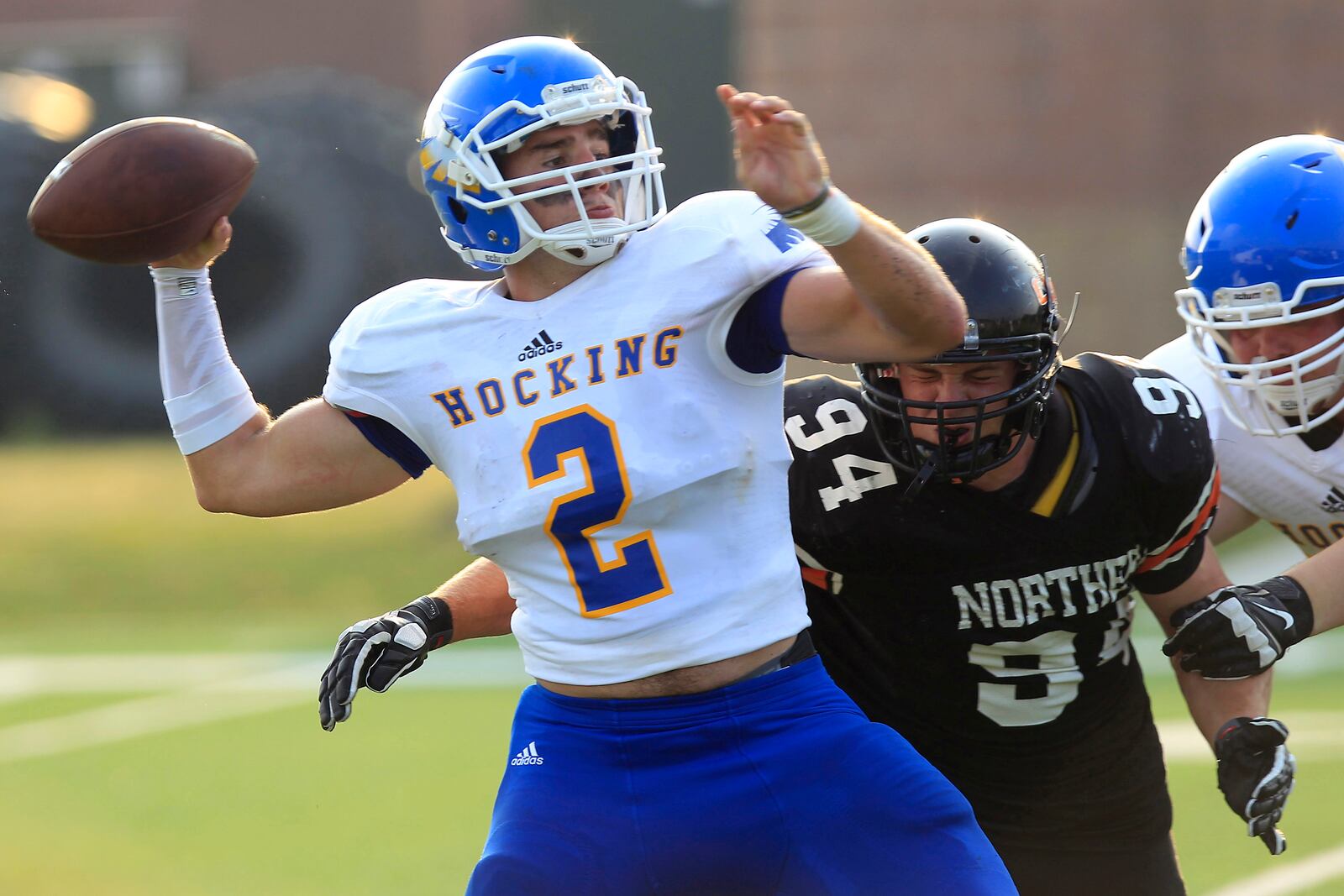 Hocking College’s Trent Mays (2) throws the ball before being hit by Ohio Northern’s Garrett Norman (94) during a football game, Monday, Aug. 31, 2015, in Ada, Ohio. With falling enrollment and a financial crisis that led to three dozen layoffs earlier this year, Hocking College officials came up with an unexpected strategy for raising the profile and attracting more students: they started a football team. (AP Photo/J.D. Pooley)