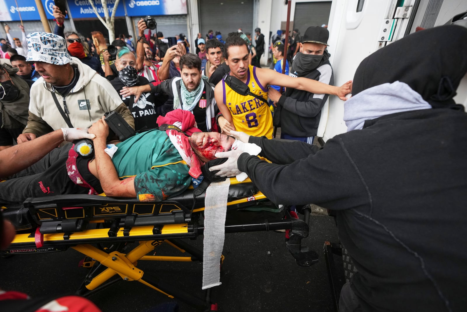 Demonstrators help transport an injured photographer onto an ambulance after clashes with police when soccer fans joined retirees protesting for higher pensions and opposing austerity measures imposed by Javier Milei's government in Buenos Aires, Argentina, Wednesday, March 12, 2025. (AP Photo/Rodrigo Abd)