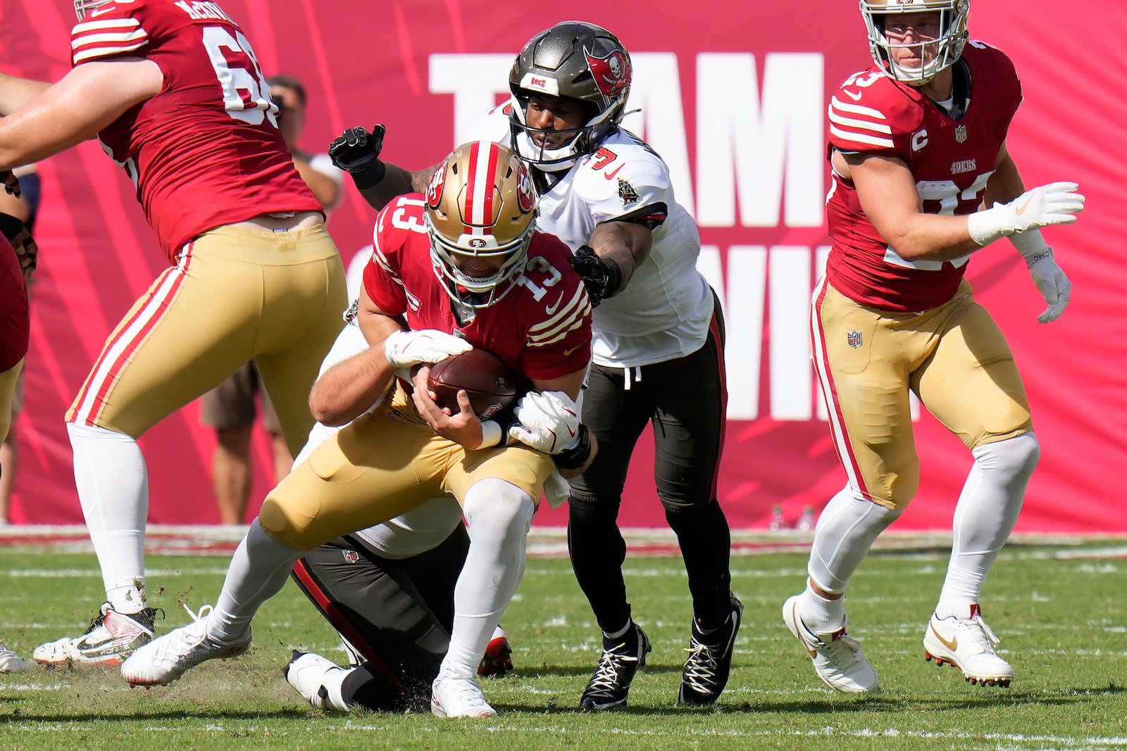 San Francisco 49ers quarterback Brock Purdy (13) is sacked by Tampa Bay Buccaneers defensive tackle Greg Gaines, bottom, as safety Jordan Whitehead (3) follows the play during the first half of an NFL football game in Tampa, Fla., Sunday, Nov. 10, 2024. (AP Photo/Chris O'Meara)