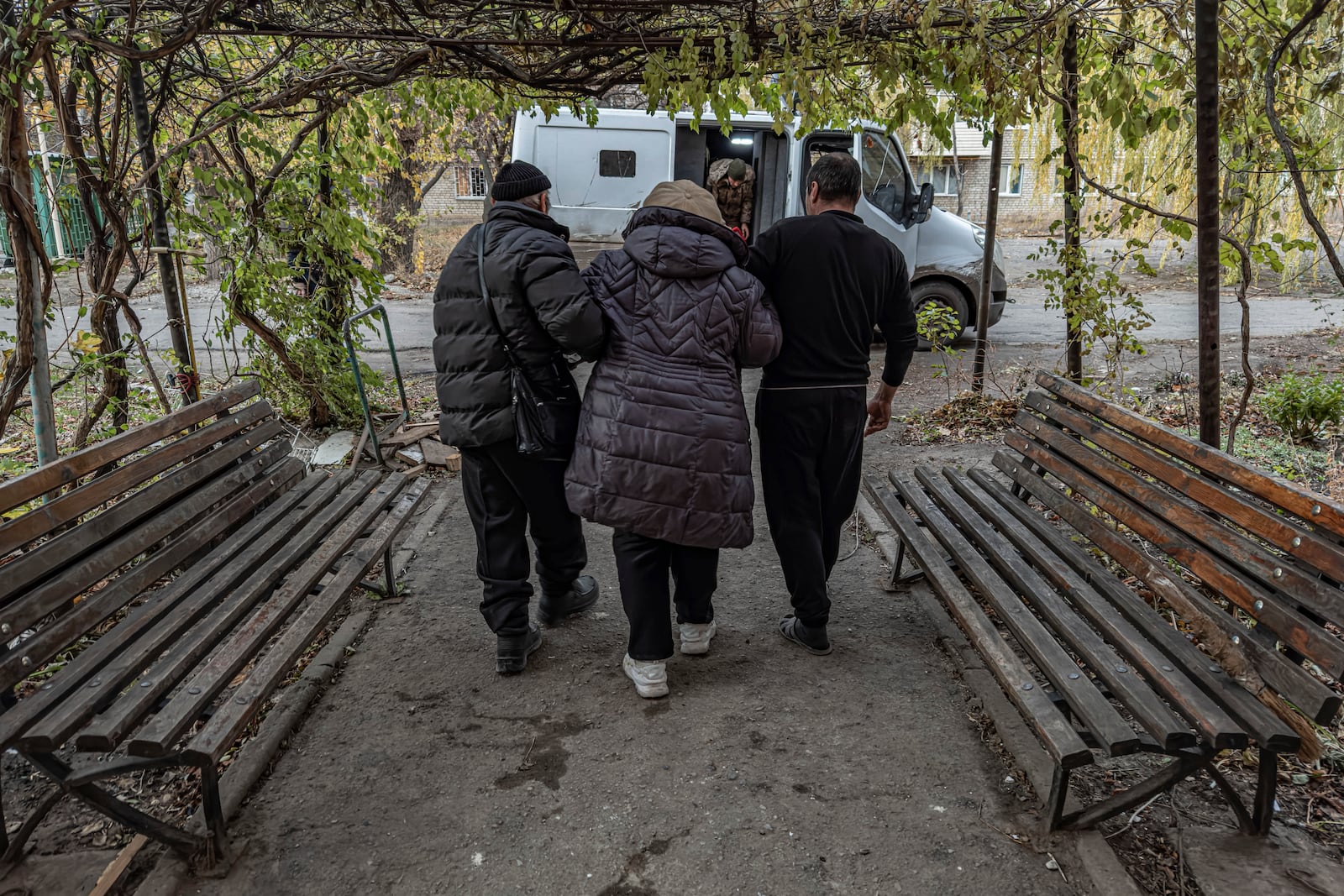 Local men help en elderly woman to walk to a police minivan during en evacuation in Kurakhove, Donetsk region, Ukraine, on Nov. 7, 2024. (AP Photo/Anton Shtuka)