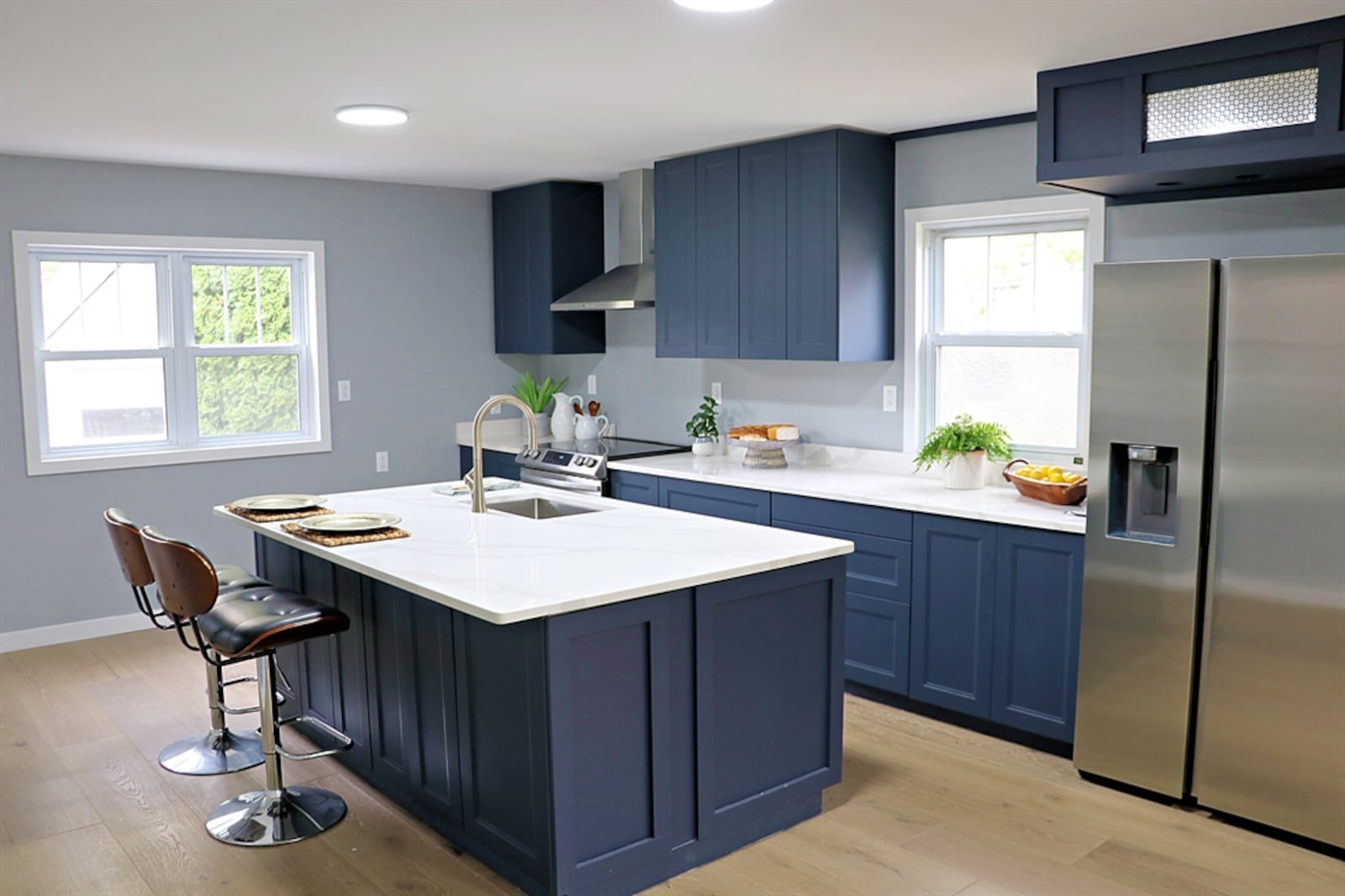 The kitchen features a large island with an extended quartz counter for bar seating. On the opposite side of the island is a single sink and dishwasher. 