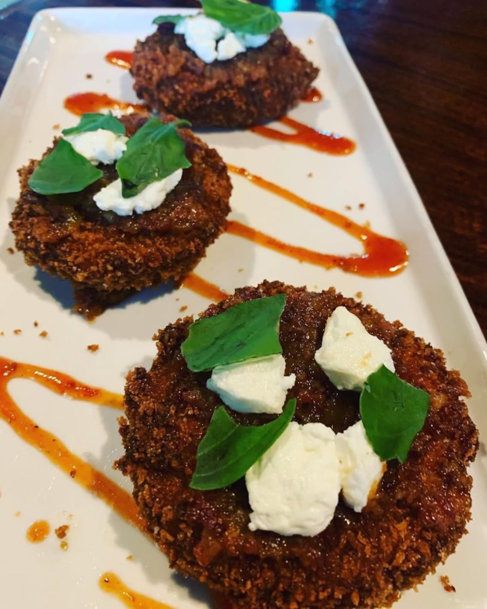 Watermark's Fried green tomatoes: A  huge seller and fan favorite featuring geeen tomatoes topped with bourbon bacon jam, goat cheese, fresh basil and smoked tomatoe coulis