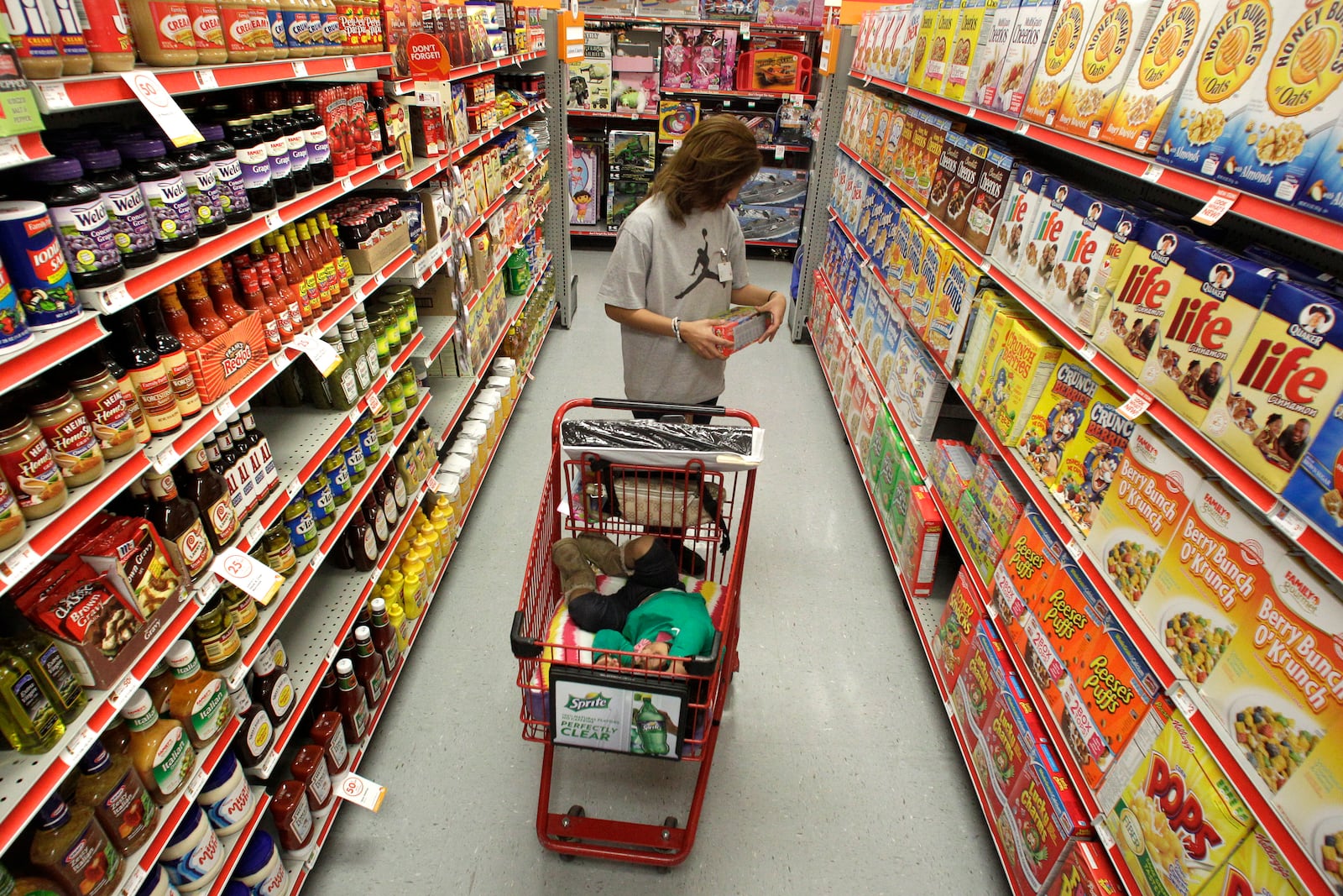 FILE - A woman looks at products in the aisle of a store as her daughter naps in the shopping cart in Waco, Texas, on Dec. 14, 2010. (AP Photo/Tony Gutierrez, File)