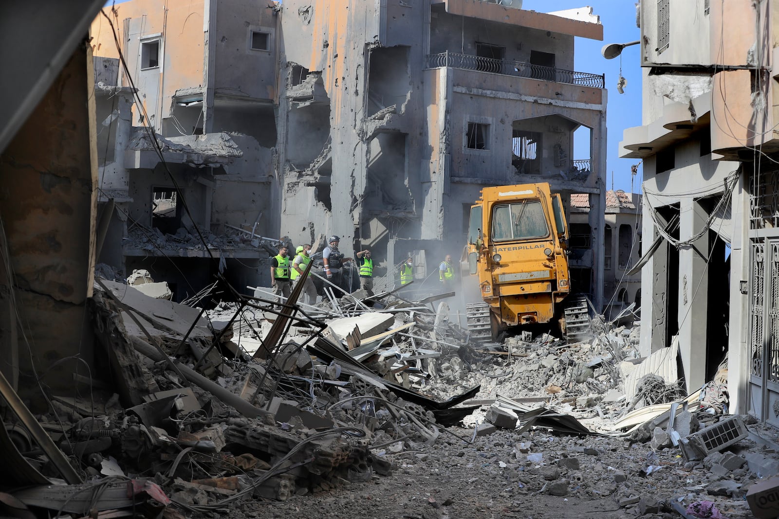 Rescue workers use a bulldozer to remove rubble of destroyed buildings, as they search for victims at the site that was hit by Israeli airstrikes in Qana village, south Lebanon, Wednesday, Oct. 16, 2024. (AP Photo/Mohammed Zaatari)