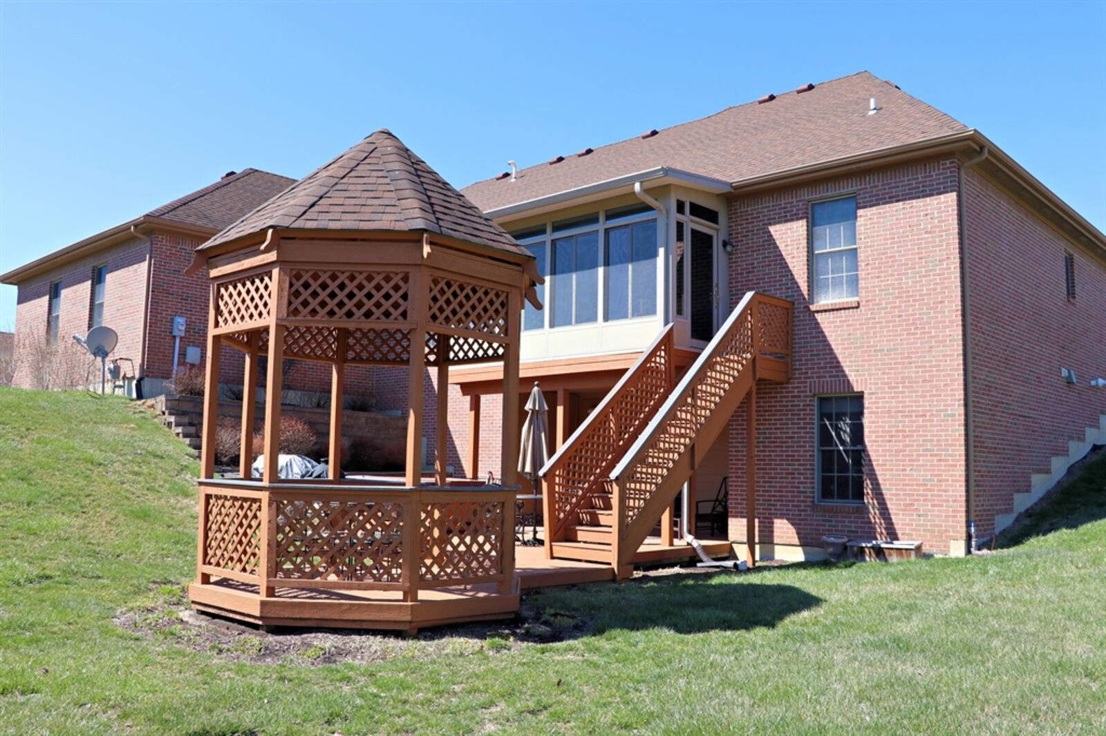 The backyard features a wooden deck, which was painted last year, and a brick terraced garden that surrounds a hot tub. The deck wraps up to a matching gazebo and steps lead up to a balcony deck off the four-season room. The near half-acre property is accented with trimmed hedges and gardens.