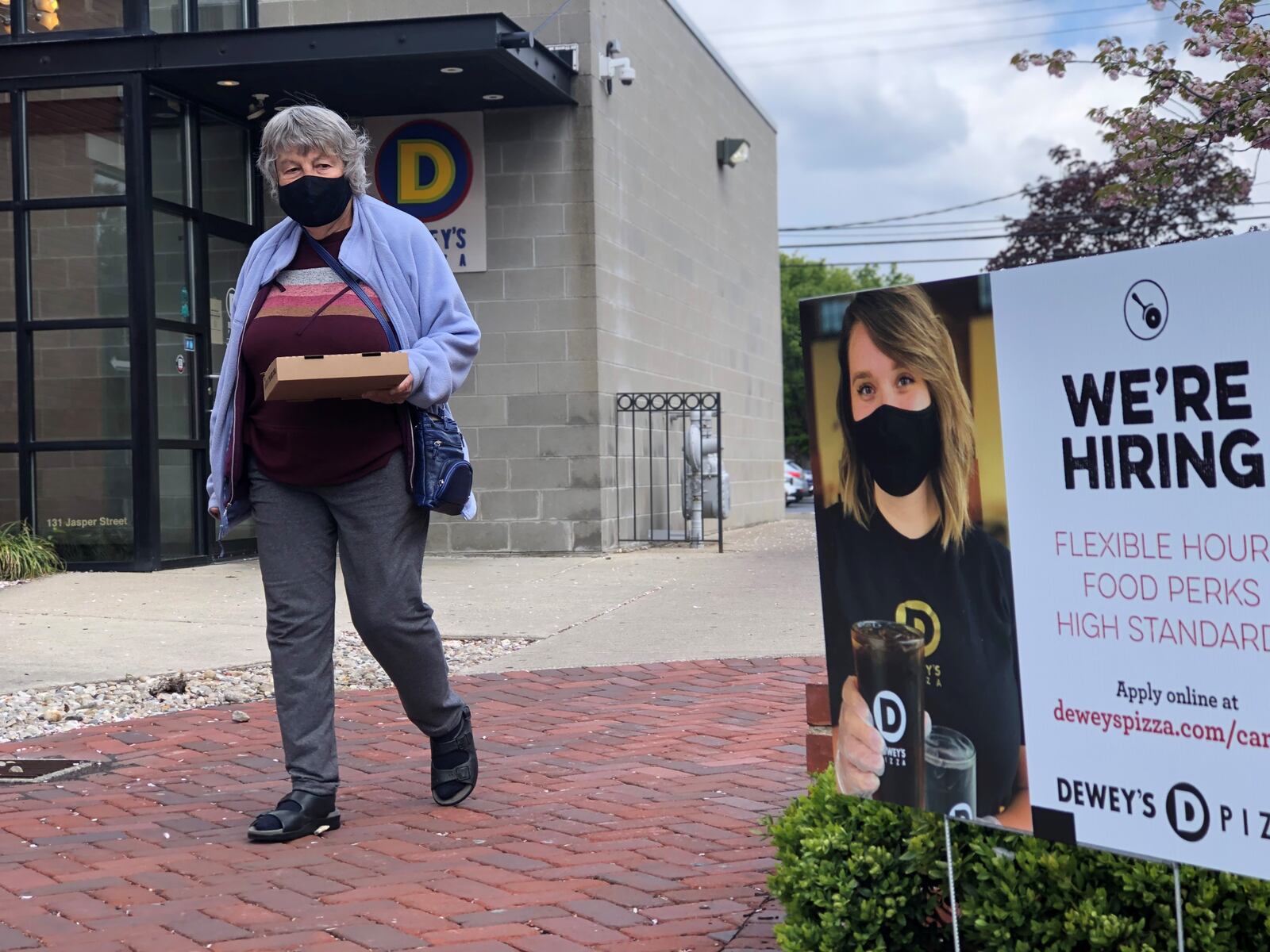 A customer of Dewey's Pizza in Dayton walks by a "We're Hiring" sign. The Dayton region added 1,200 jobs last month. CORNELIUS FROLIK / STAFF