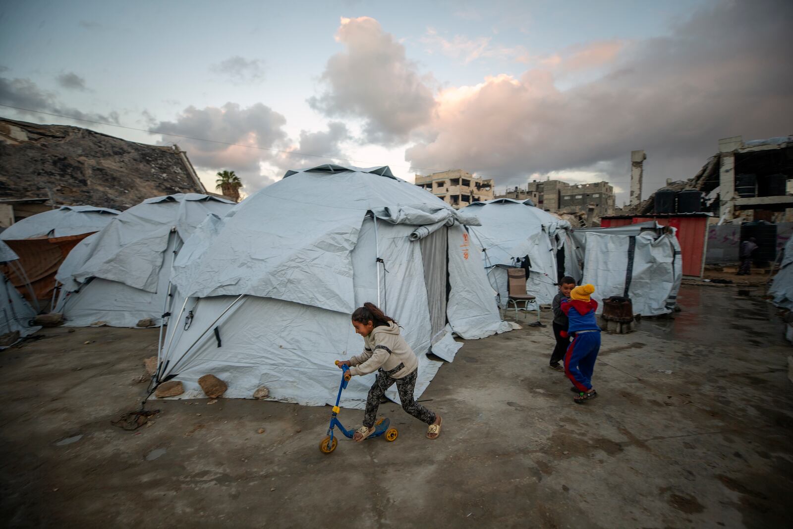 Children play at a tent camp for displaced Palestinians in Gaza City's Jabalya refugee camp, Thursday, Feb. 6, 2025, after collecting donated food. (AP Photo/Jehad Alshrafi)