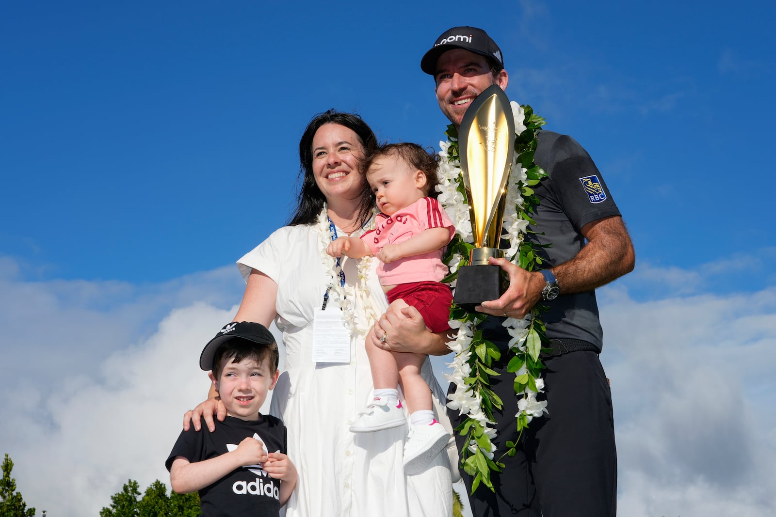 Nick Taylor, right, of Canada, poses with his wife, Andie Taylor, and his children, Charlie Taylor, left, and Harper Taylor, center, after winning the Sony Open golf event, Sunday, Jan. 12, 2025, at Waialae Country Club in Honolulu. (AP Photo/Matt York)