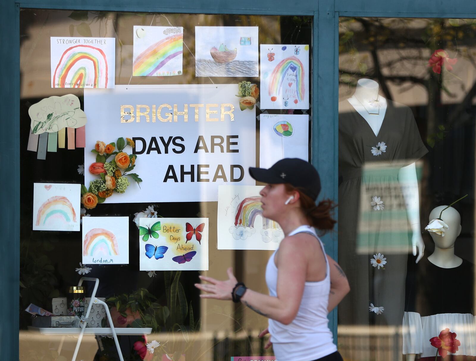 A runner jogs past a positive message in the window of the beck + call boutique in Dayton's Oregon Historic District. LISA POWELL / STAFF