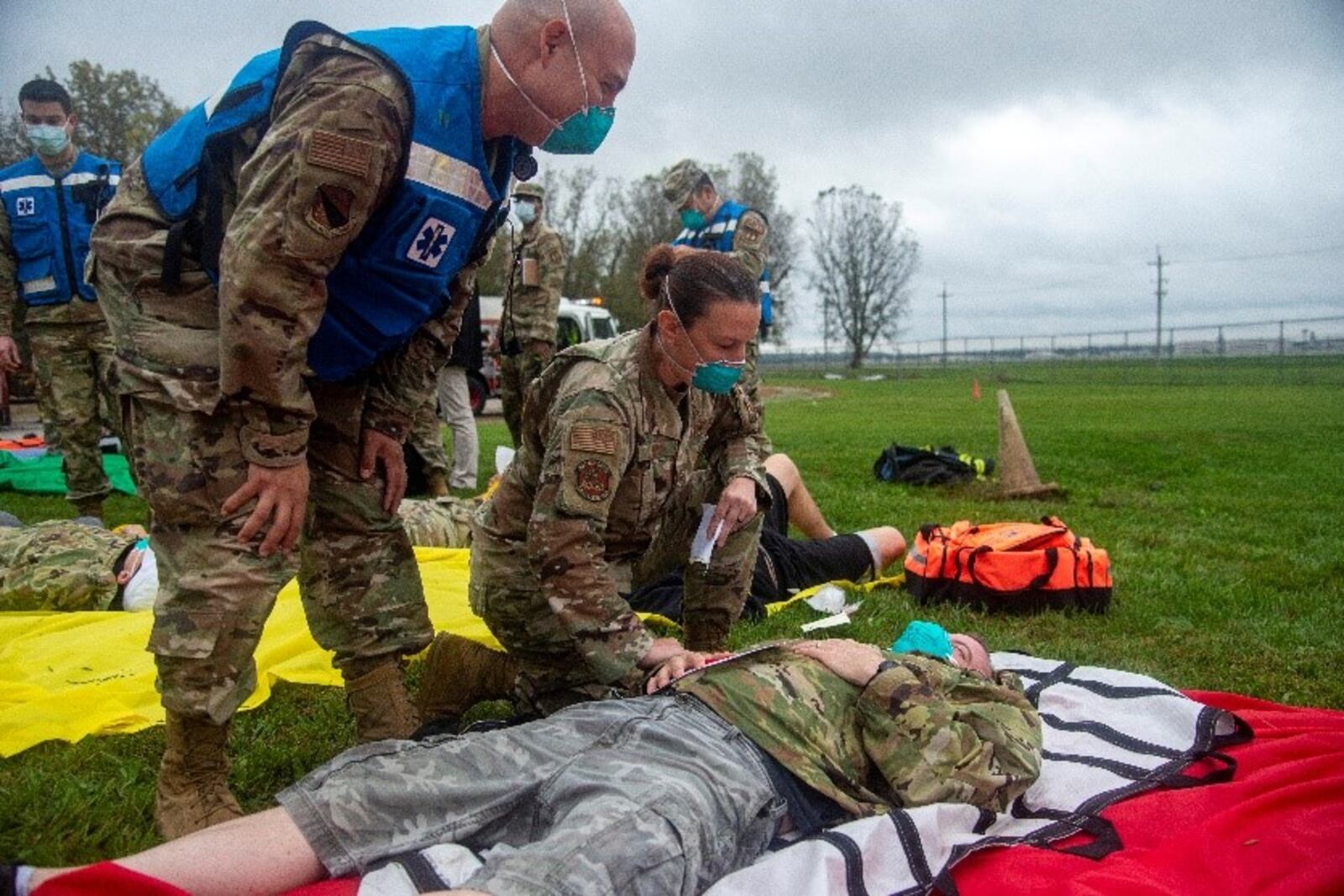 A role player pretends to be in pain while medical personnel compare notes in the triage area on the scene of a simulated C-17 aircraft crash as part of an exercise Oct. 7 at Wright-Patterson Air Force Base. Readiness exercises are routinely held to streamline unit cohesion when responding to emergencies. (U.S. Air Force photo by Jack Gardner)