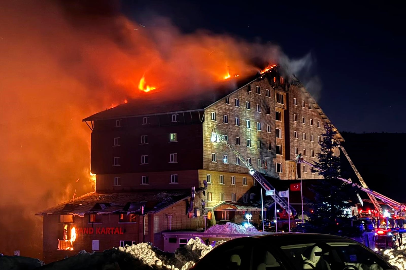 Firefighters work to extinguish a fire in a hotel at a ski resort of Kartalkaya in Bolu province, in northwest Turkey, Tuesday, Jan. 21, 2025. (IHA via AP)