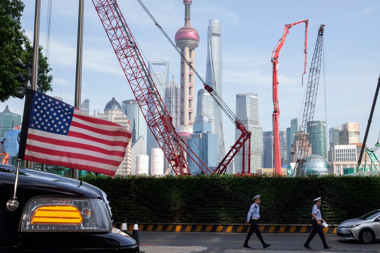 FILE - Chinese traffic police officers walk by a U.S. flag on an embassy car outside a hotel in Shanghai where officials from both sides met for talks aimed at ending a tariff war on July 30, 2019. (AP Photo/Ng Han Guan, File)