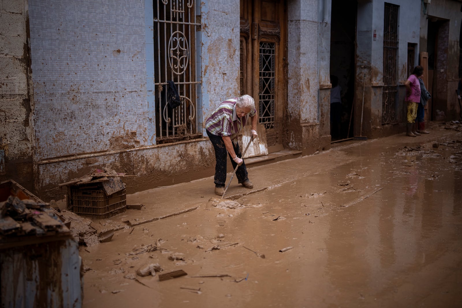 Maria Munoz, 74, cleans the mud outside her house, where she was born and which was badly affected by flooding in Masanasa, Valencia, Spain, Wednesday, Nov. 6, 2024. (AP Photo/Emilio Morenatti)