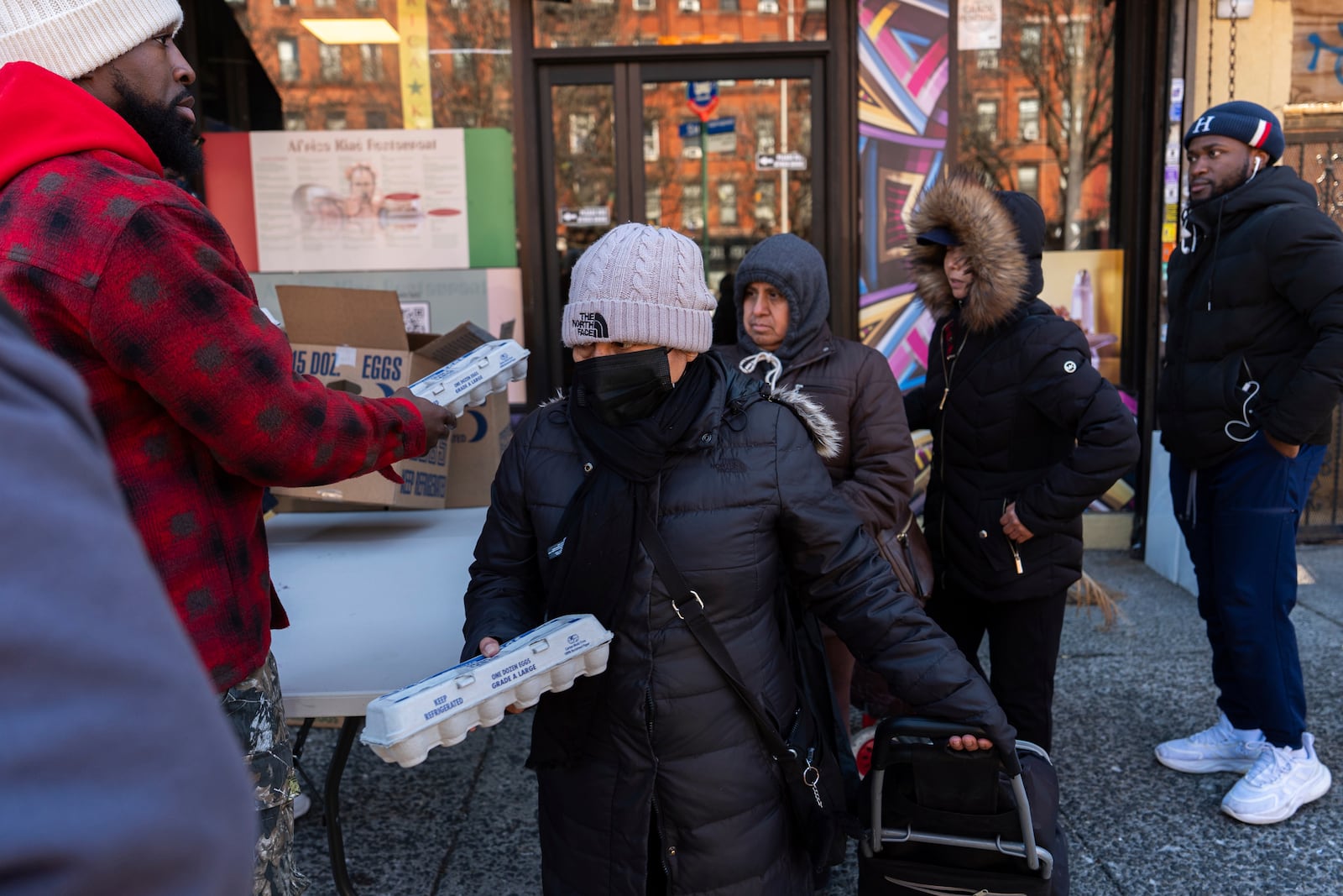 Abou Sow hands out cartons of eggs to people waiting in line to receive free eggs from FarmerJawn Agriculture, Friday, March 21, 2025, in the Harlem neighborhood of New York. (AP Photo/Julia Demaree Nikhinson)