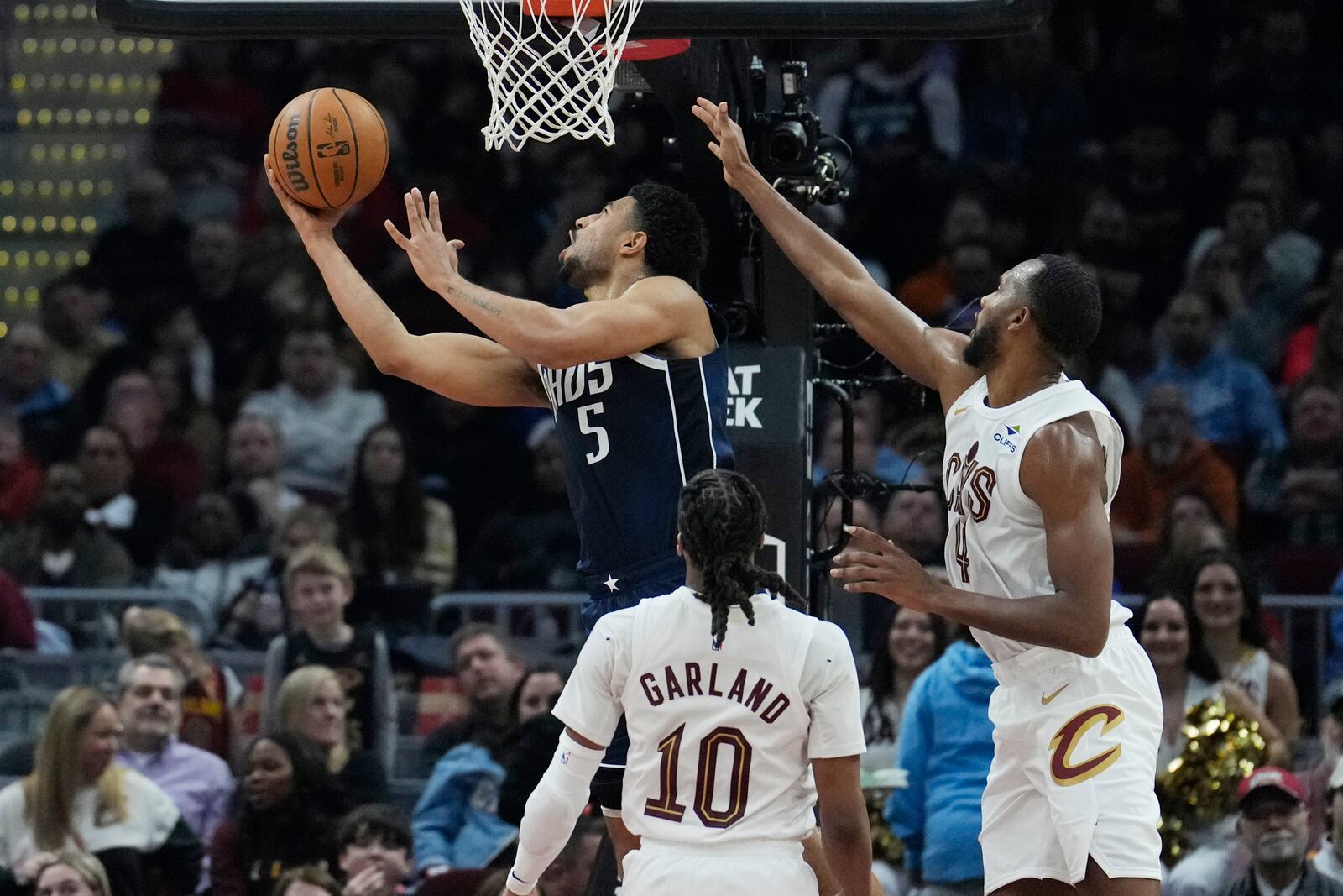 Dallas Mavericks guard Quentin Grimes (5) shoots in front of Cleveland Cavaliers guard Darius Garland (10) and Evan Mobley, right, in the first half of an NBA basketball game, Sunday, Feb. 2, 2025, in Cleveland. (AP Photo/Sue Ogrocki)