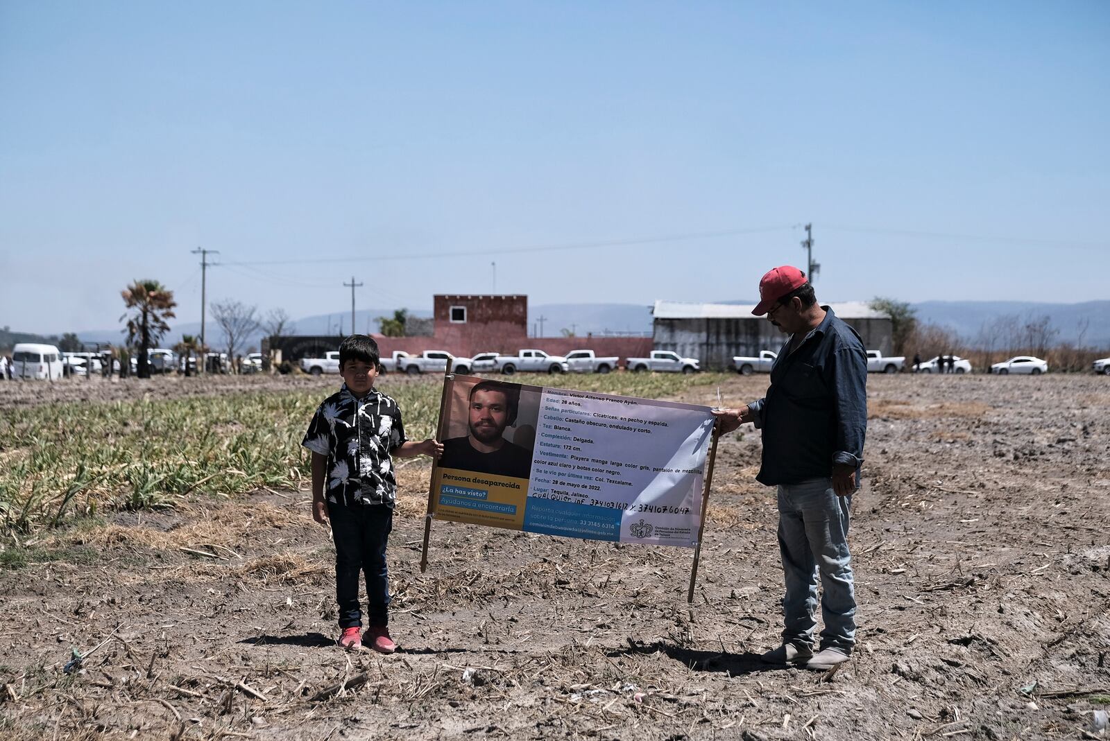 People hold a photo of a missing relative outside Izaguirre Ranch where skeletal remains were discovered in Teuchitlan, Jalisco state, Mexico, Thursday, March 13, 2025. (AP Photo/Alejandra Leyva)