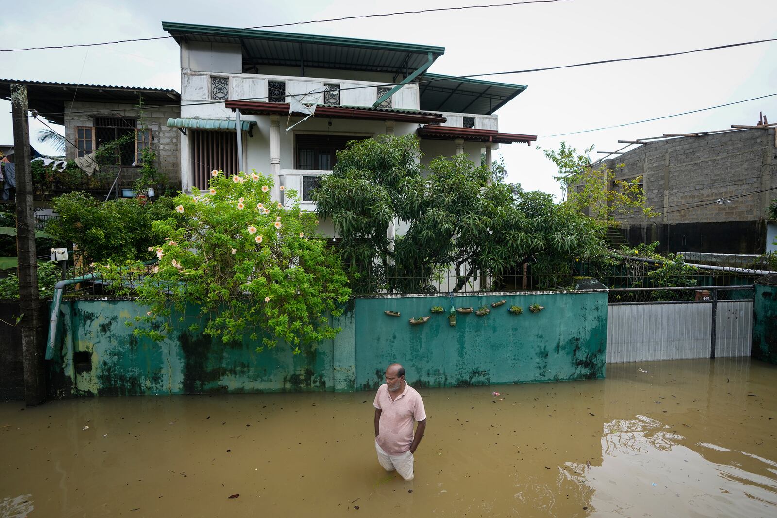 A man wades through his flooded neighborhood in Colombo, Sri Lanka, Monday, Oct. 14, 2024. (AP Photo/Eranga Jayawardena)