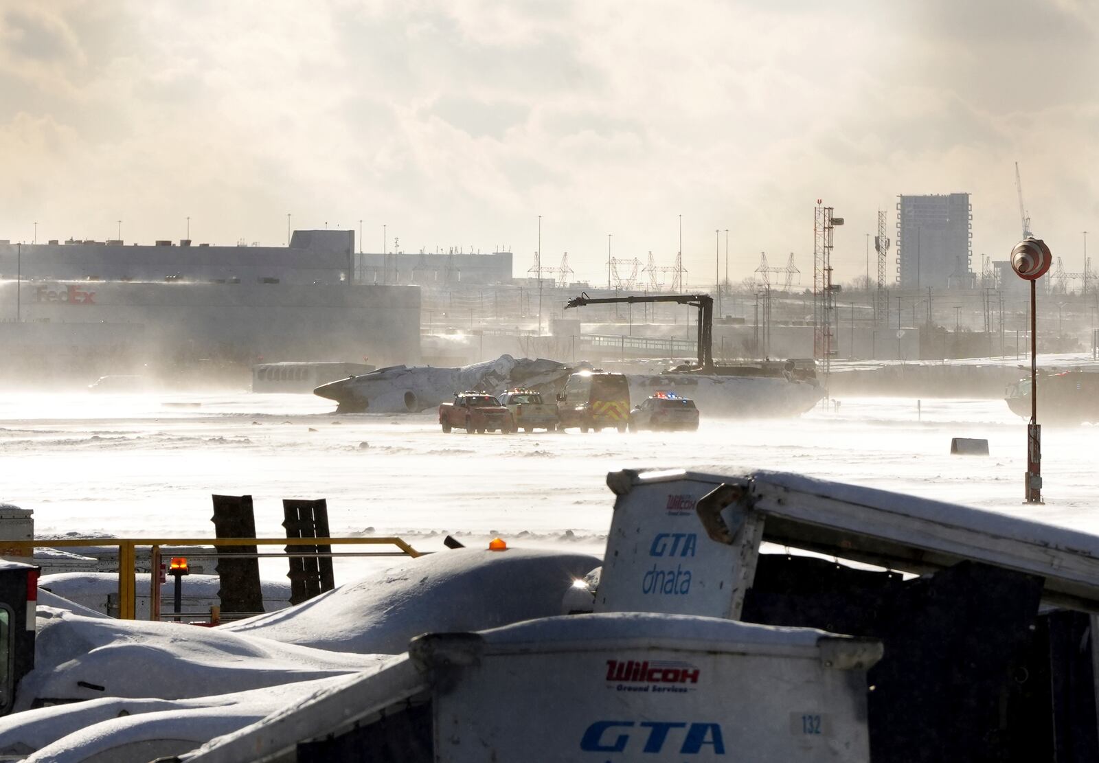 Emergency response vehicles are seen nearby an upside down Delta Air Lines plane, which was heading from Minneapolis to Toronto when it crashed on the runway at Pearson International Airport, in Toronto, Monday, Feb. 17, 2025. (Teresa Barbieri/The Canadian Press via AP)