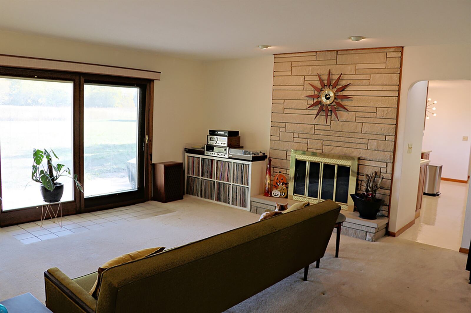 A casual family room has a light stone wall that surrounds the fireplace opening. Brass-framed glass doors open into the fire pit, and a raised hearth has a stone top. CONTRIBUTED PHOTO BY KATHY TYLER