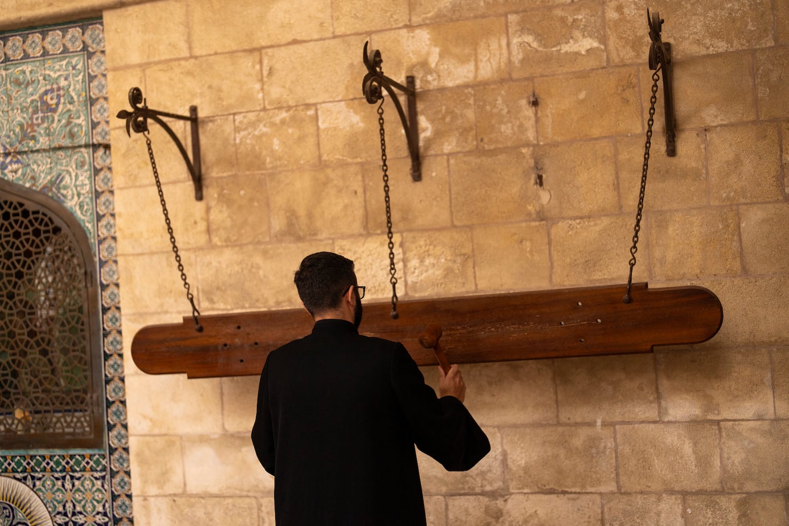 A member of the Armenian clergy uses a wood hammer to call for the daily afternoon prayer service at St. James Cathedral at the Armenian quarter in Jerusalem, Thursday, Nov. 21, 2024. (AP Photo/Francisco Seco)