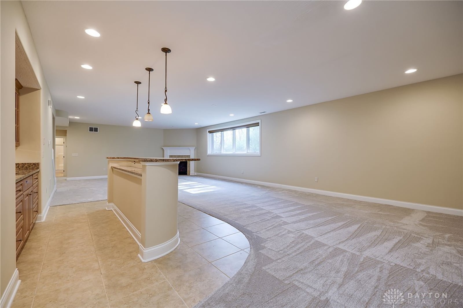 the finished basement has a recreation room with corner gas fireplace and wet bar with pendant lighting.