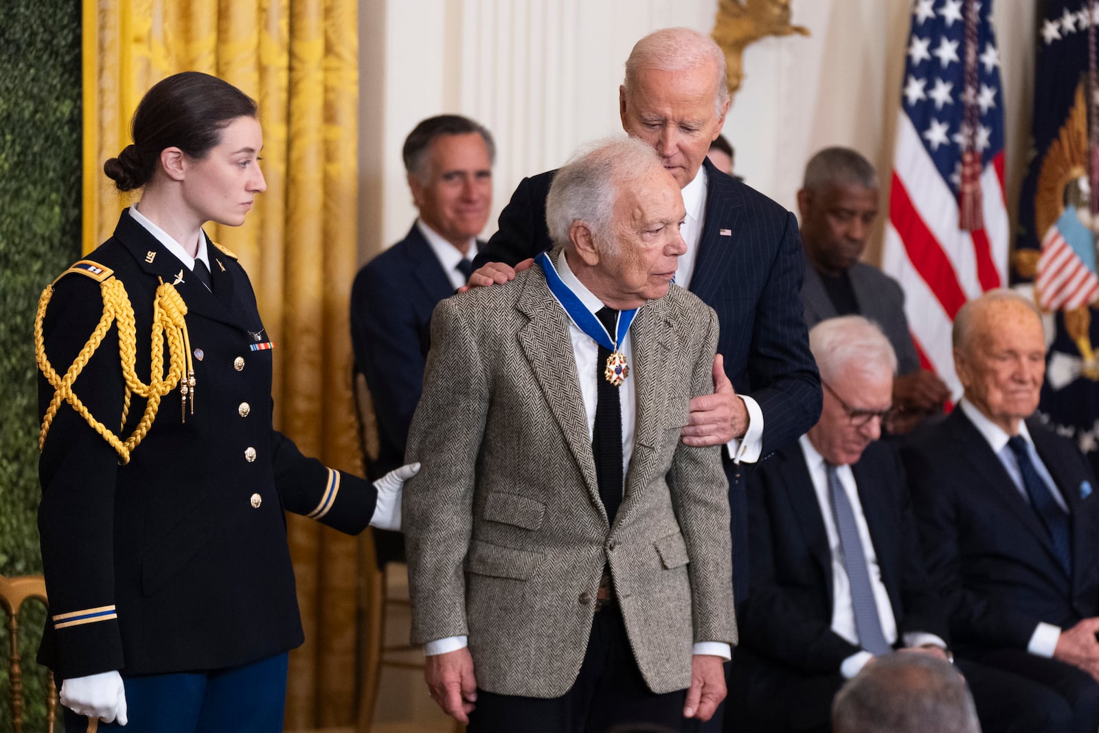 FILE - Army Capt. Rebecca M. Lobach, from left, of Durham, N.C., escorts fashion designer Ralph Lauren as President Joe Biden presents Lauren with the Presidential Medal of Freedom in the East Room of the White House, Jan. 4, 2025, in Washington. (AP Photo/Manuel Balce Ceneta, File)