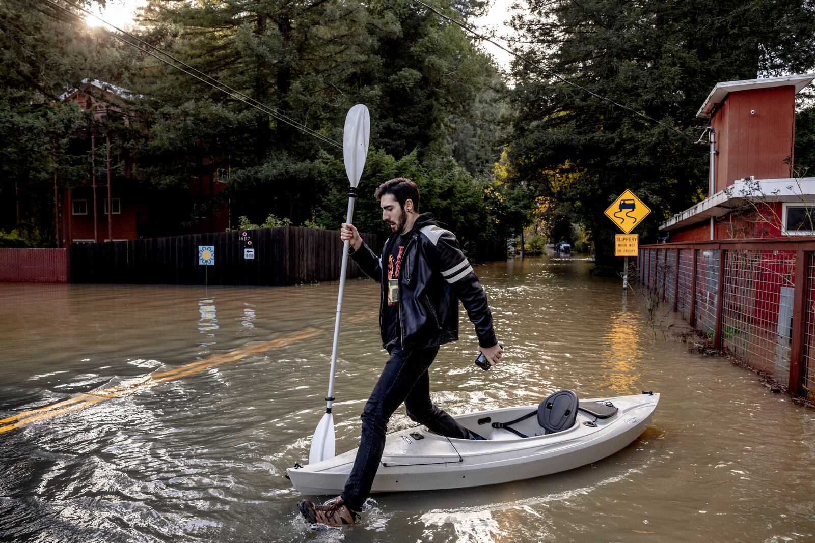 Tristan Millstone reacts as he steps in water after kayaking across a flooded section of Neely Road to buy groceries after a major storm in Guerneville, Calif., Saturday, Nov. 23, 2024. (Stephen Lam/San Francisco Chronicle via AP)