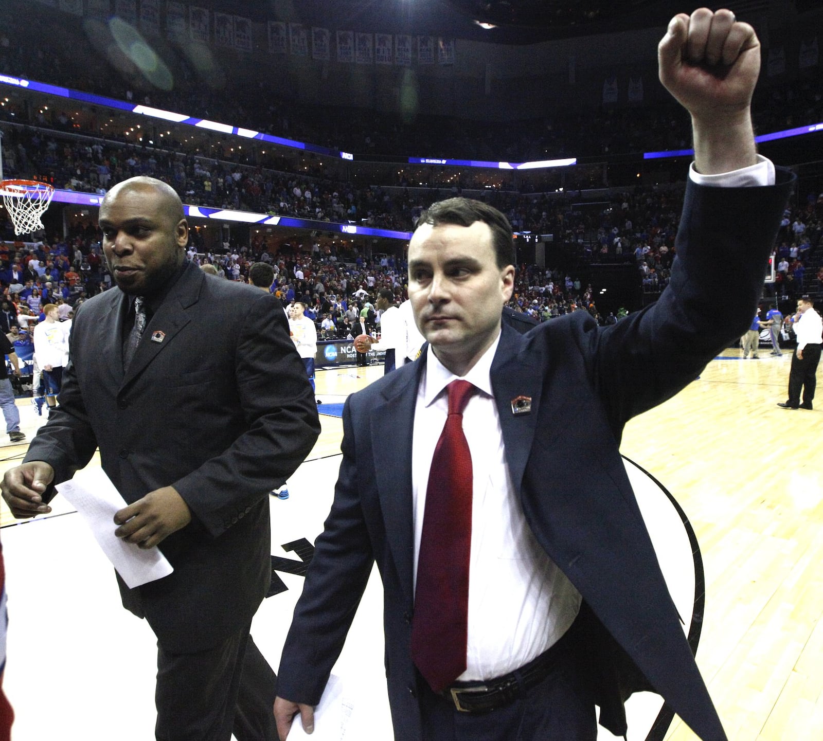 Dayton head coach Archie Miller, right, and graduate assistant Simon Harris leave the court after a victory over Stanford in the Sweet 16 at FedExForum in Memphis, Tenn., on March 27, 2014. David Jablonski/Staff