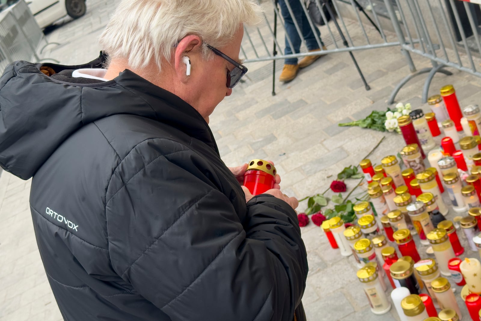 A man lights a candle at the site of stabbing a day after an attack that left a 14-year-old dead and five others injured, in Villach, Austria, Sunday, Feb. 16, 2025. (AP Photo/Darko Bandic)