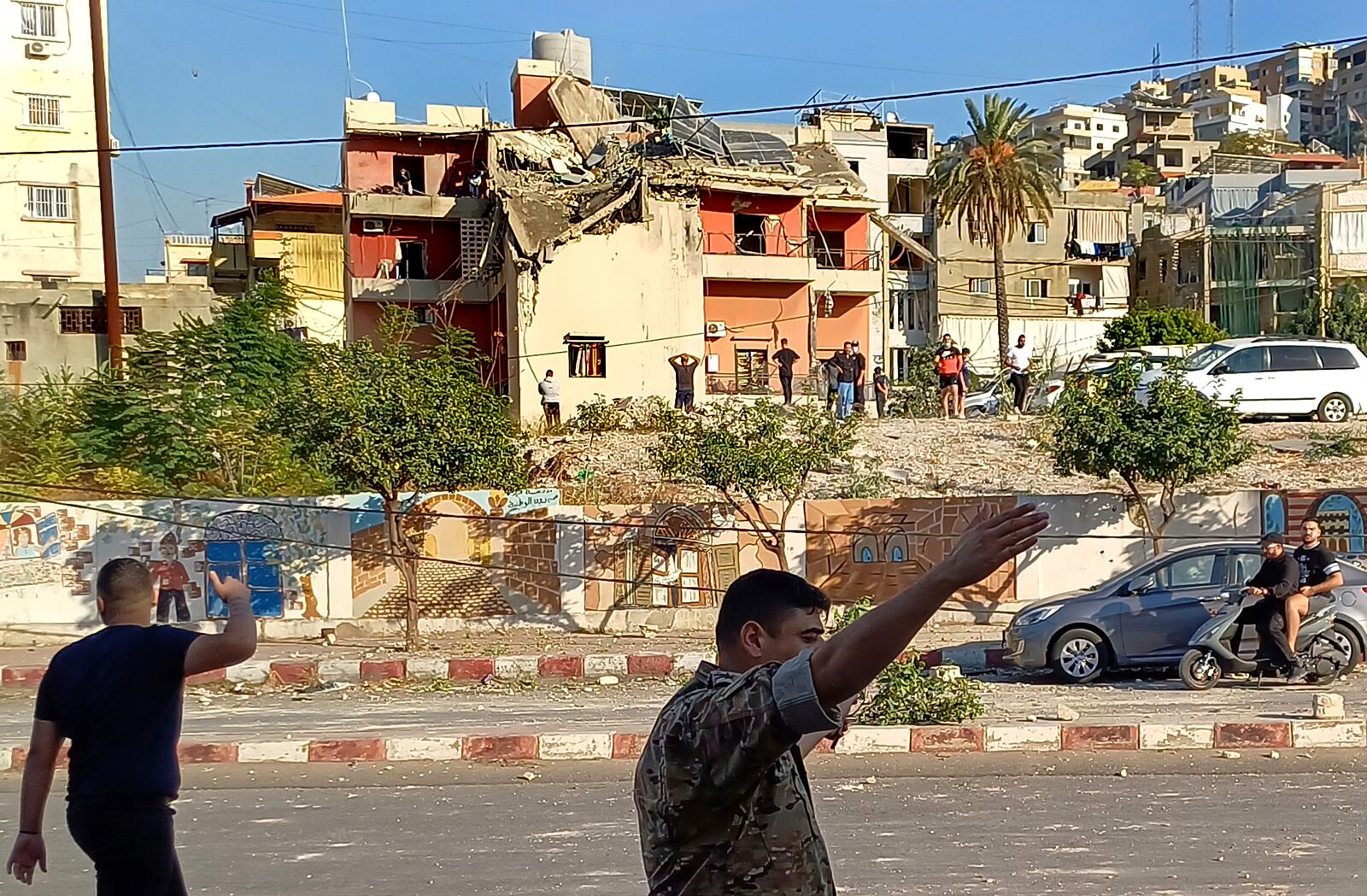 A Lebanese soldier asks journalists to move away from the scene near a building hit in an Israeli airstrike, in the southern port city of Sidon, Lebanon, Sunday, Oct. 27, 2024. (AP Photo/Mohammad Zaatari)