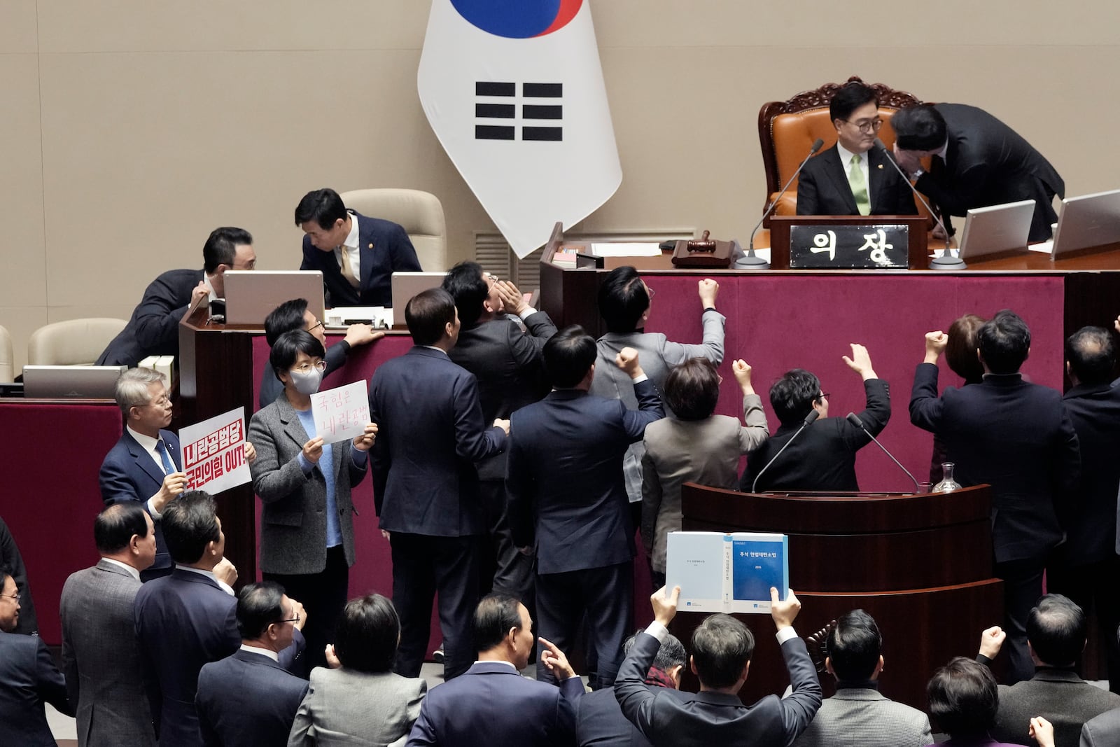 Lawmakers, left, of South Korea's opposition Democratic Party, hold signs as lawmakers of the ruling People Power Party protesting to South Korea's National Assembly Speaker Woo Won Shik, top second from right, during a plenary session for the impeachment motion against South Korean acting President Han Duck-soo at the National Assembly in Seoul, South Korea, Dec. 27, 2024. The signs read "People Power Party is an accomplice of rebellion". (AP Photo/Ahn Young-joon)