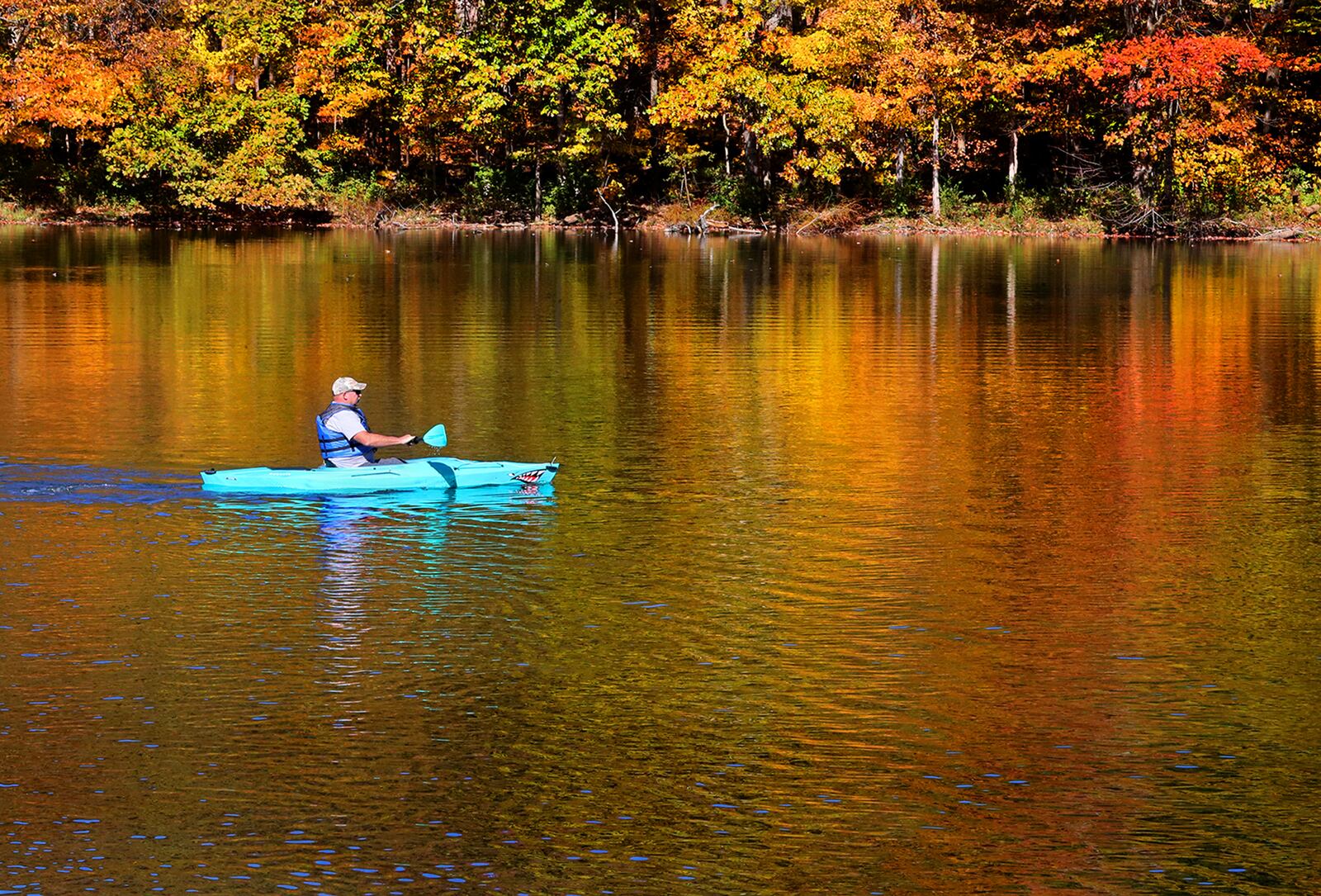 Dale Amsden glides across the fall colors reflected in the Hosterman Lake at George Rogers Clark Park in his kayak Monday. Amsden had just got the kayak and was testing it out before taking it on a trip. BILL LACKEY/STAFF