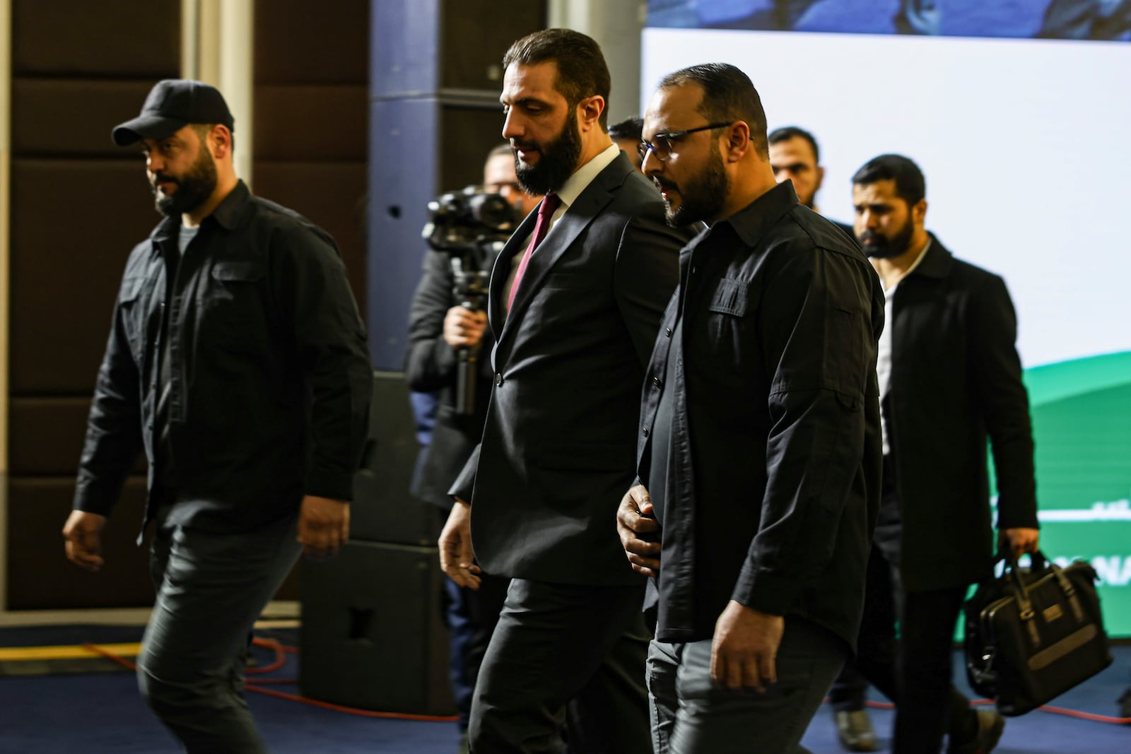 Syria's interim president Ahmad al-Sharaa, center, arrives to speak at Syria's national dialogue conference at the Dama Rose hotel in Damascus, Syria, Tuesday Feb. 25, 2025.(AP Photo/Omar Albam)