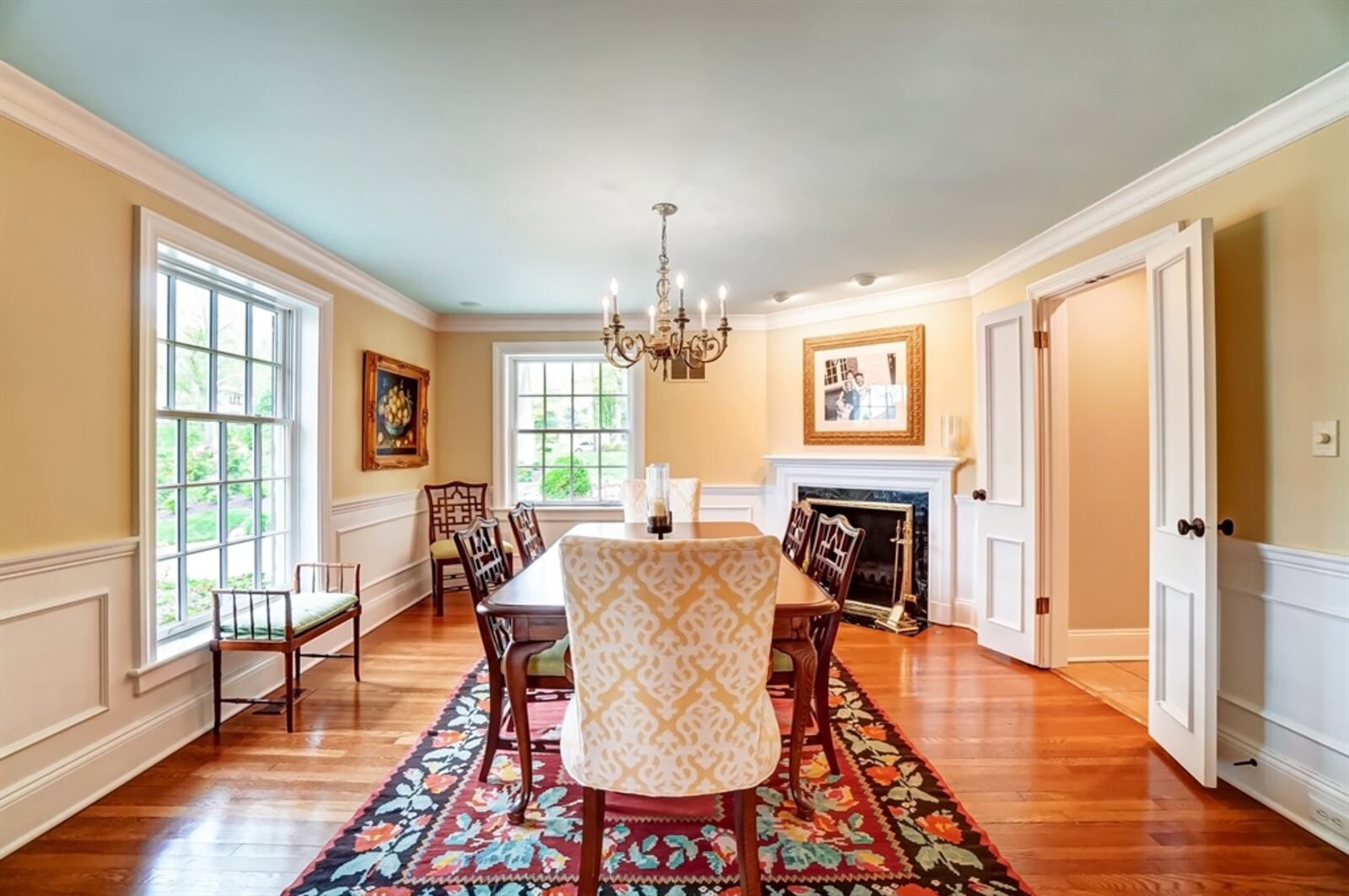 The dining room has a gas fireplace with marble surround and a wood mantel that blends into the wainscoting.