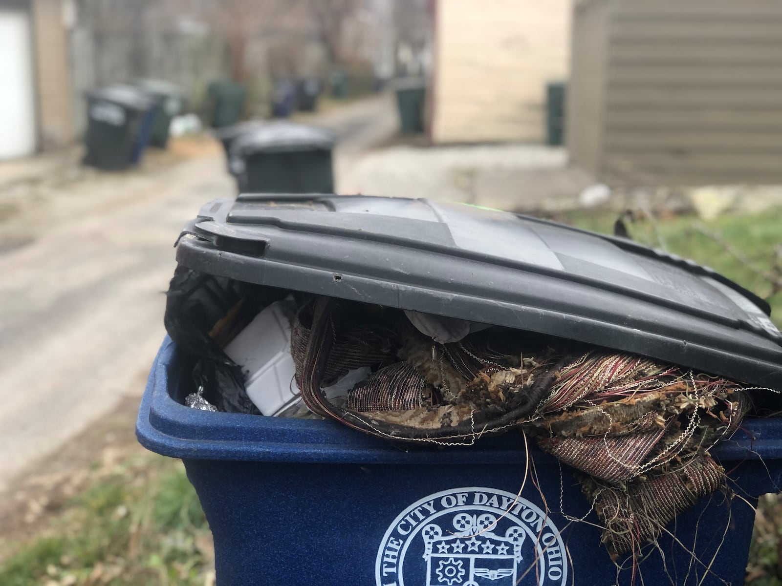 Dayton sanitation crews put an "oops" warning sticker on this blue recycling bin in the South Park neighborhood because it was contaminated with trash. The recycling bin contained fabric and other nonrecyclable materials that belong in the landfill. CORNELIUS FROLIK / STAFF